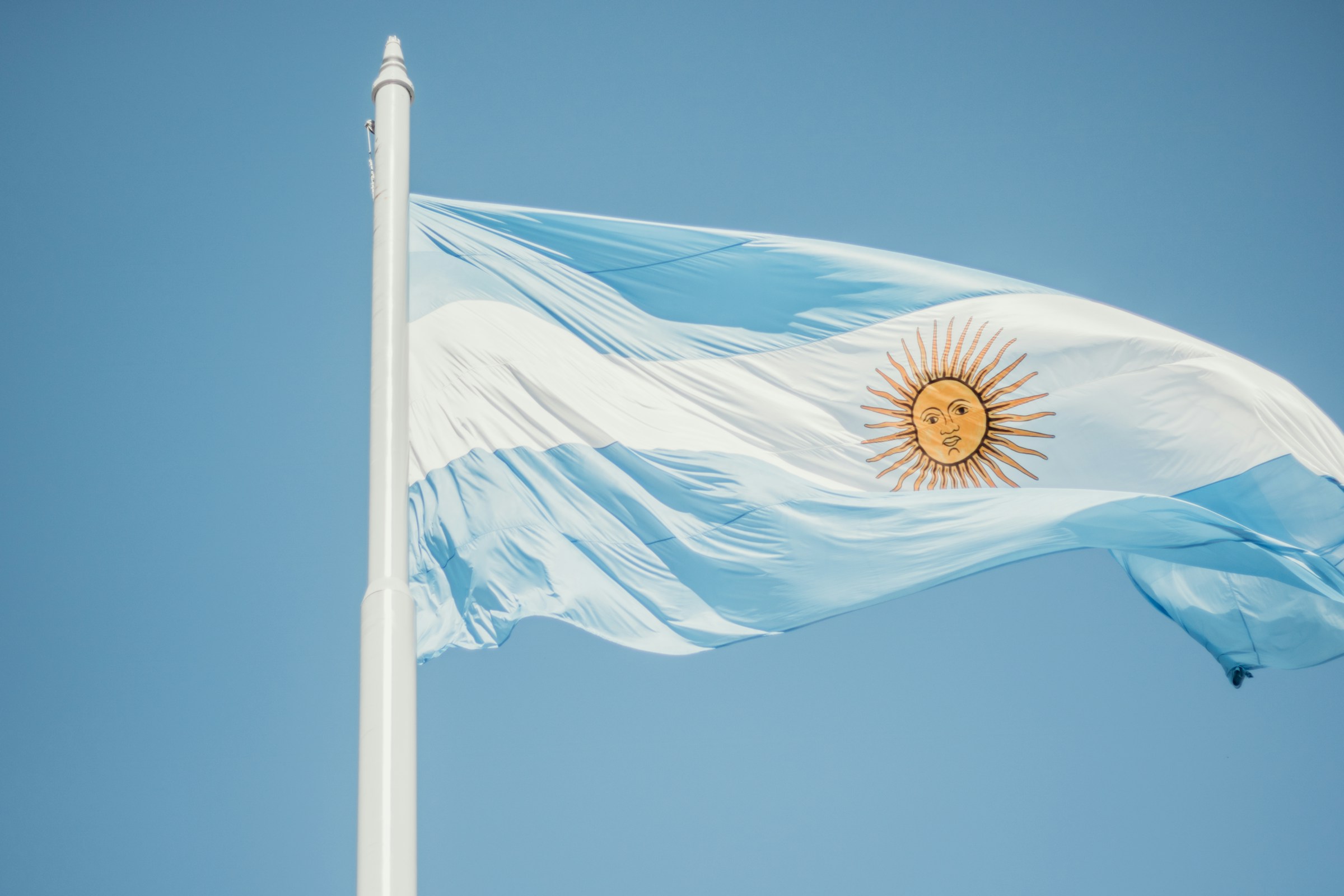 Argentinas flagga vajar mot en klarblå himmel.