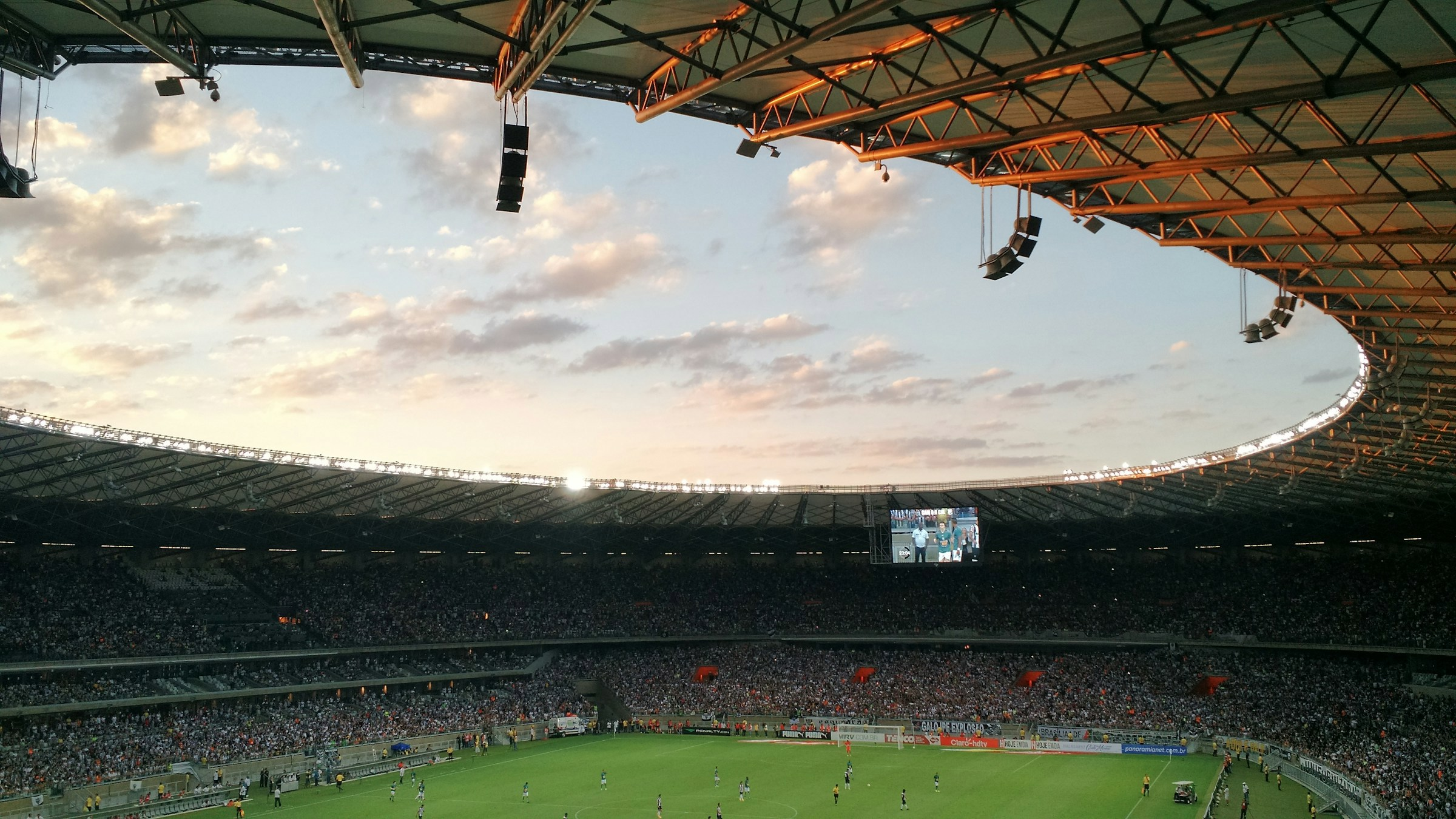 Solnedgång över ett fullsatt stadion under en fotbollsmatch 