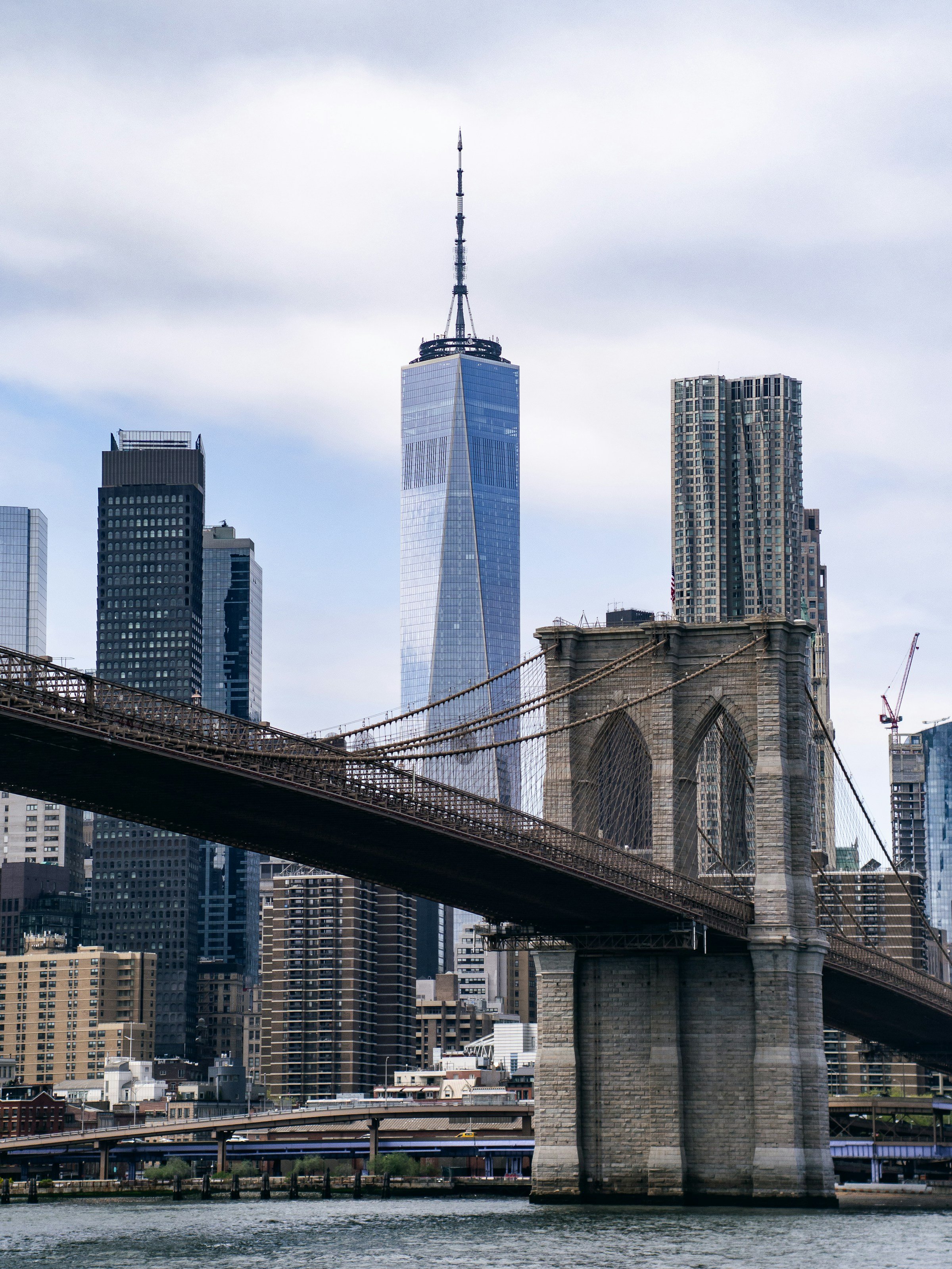 Brooklyn Bridge i New York stränger sig över en flod med skyskrapor i Manhattan i bagrkunden