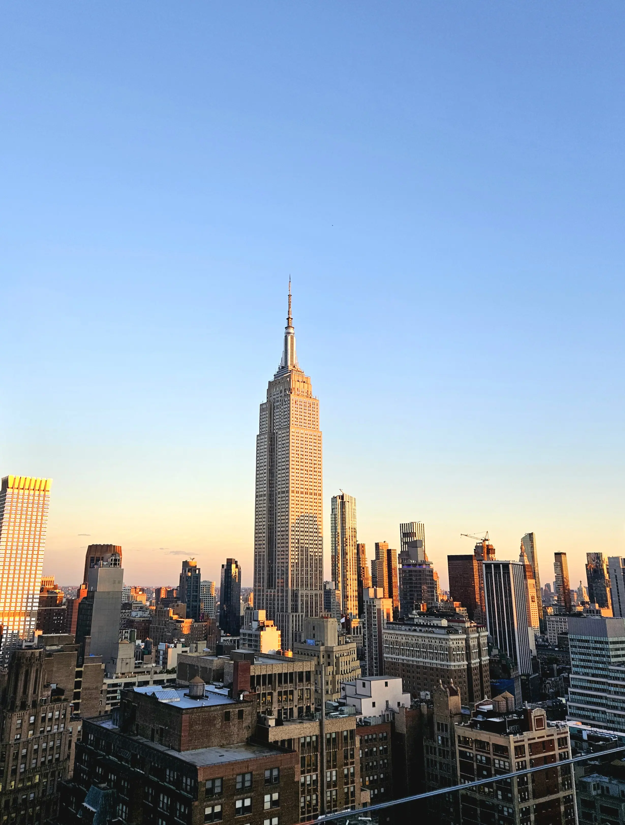 Bild över New York City med fokus på Empire State Buildning med blå himmel i bakgrunden