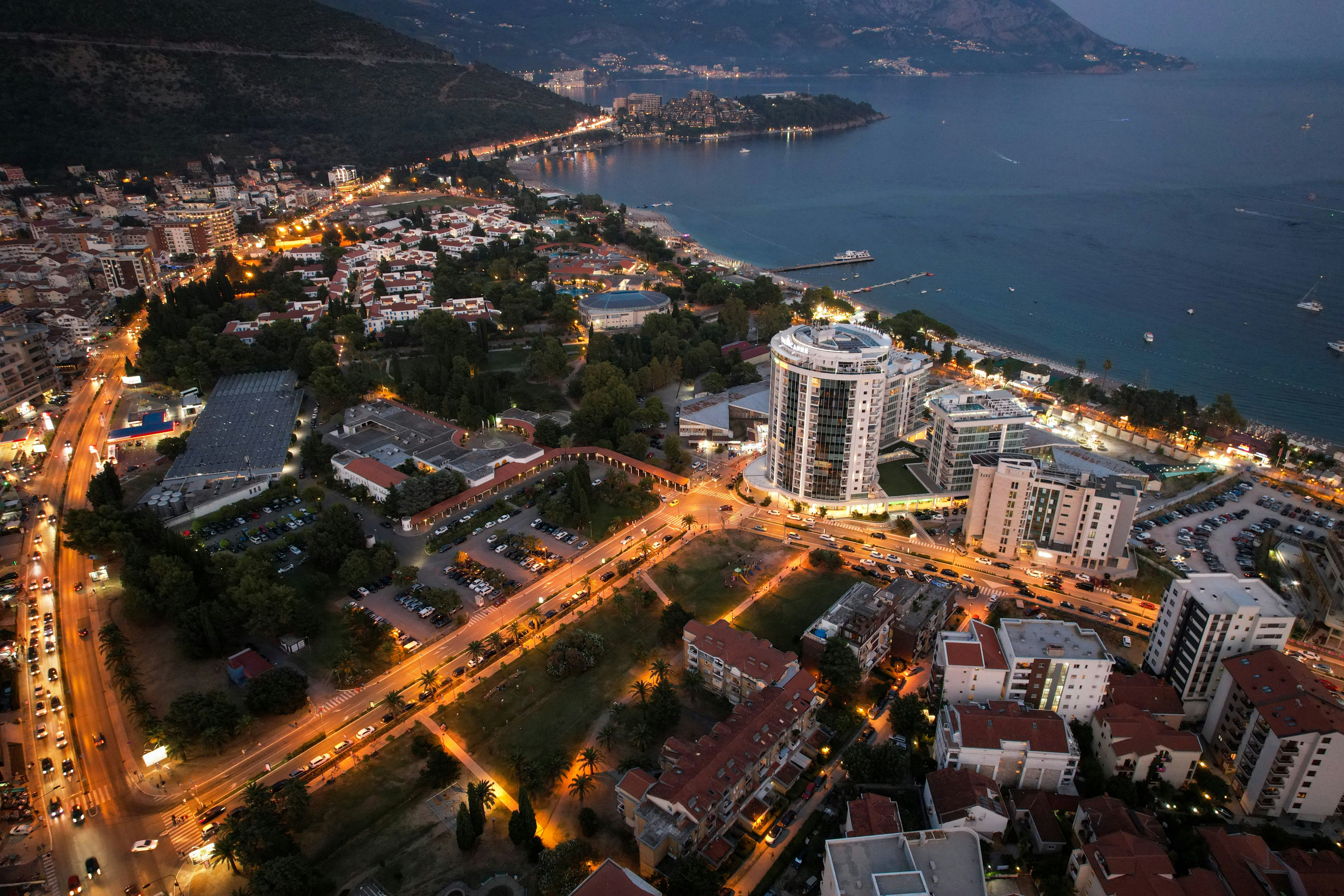 Travel to Tirana - Bird's-eye view of Tirana in Albania during evening hours with city lights and roads illuminating the city's buildings