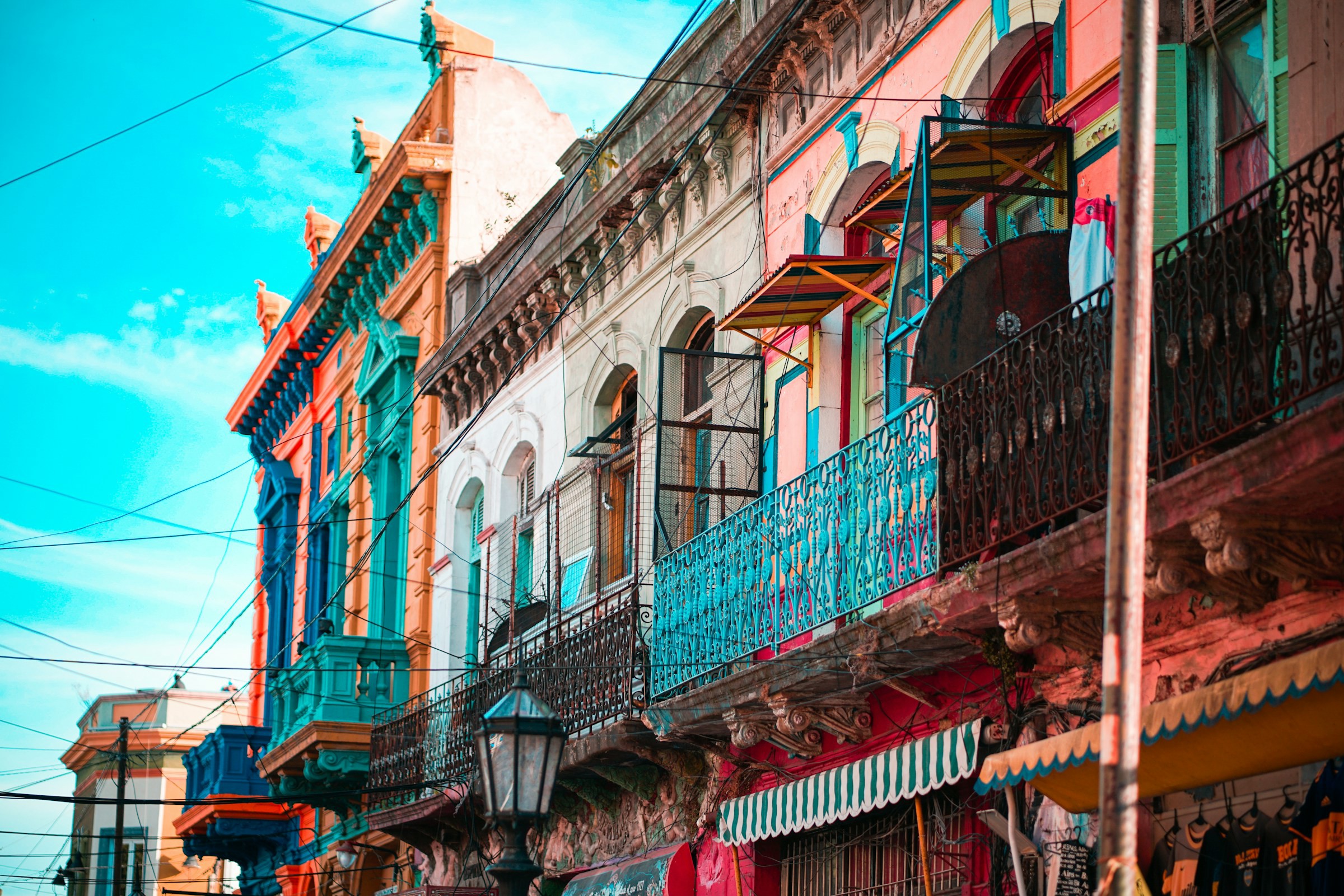 Colorful historic buildings with wrought iron balconies in La Boca, Buenos Aires, under a clear blue sky.