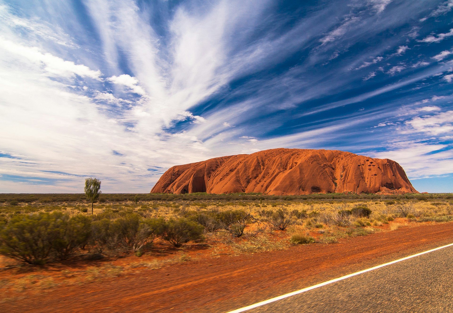 Uluru (Ayers Rock) i Australien med dramatisk himmel och ökenlandskap.