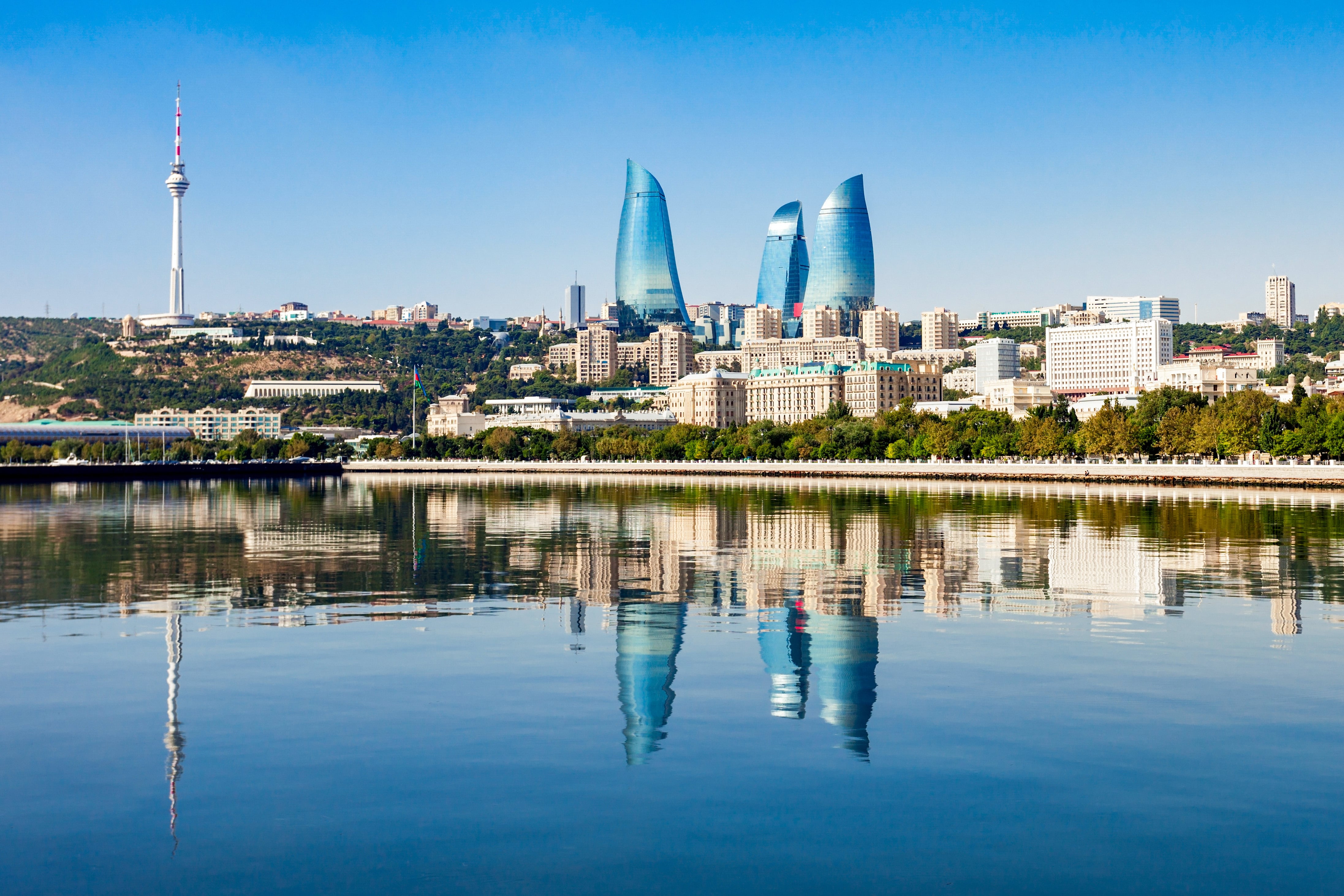 Travel to Baku - Sea meets Baku city with skyscrapers reaching a blue sky with green trees all around it