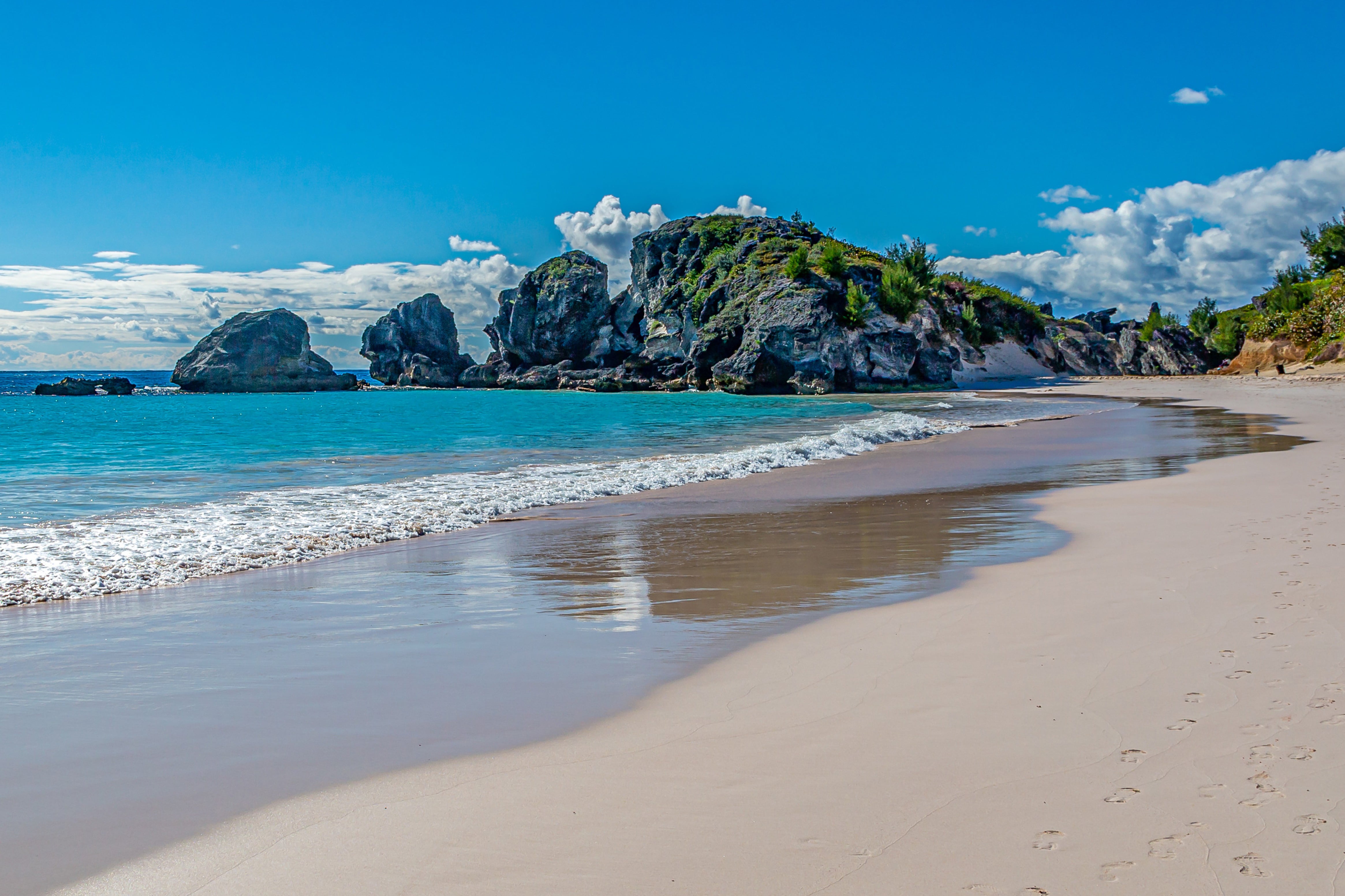 Travel to Bermuda - Beautiful quiet white beach with turquoise blue water with rocks and blue sky in the background