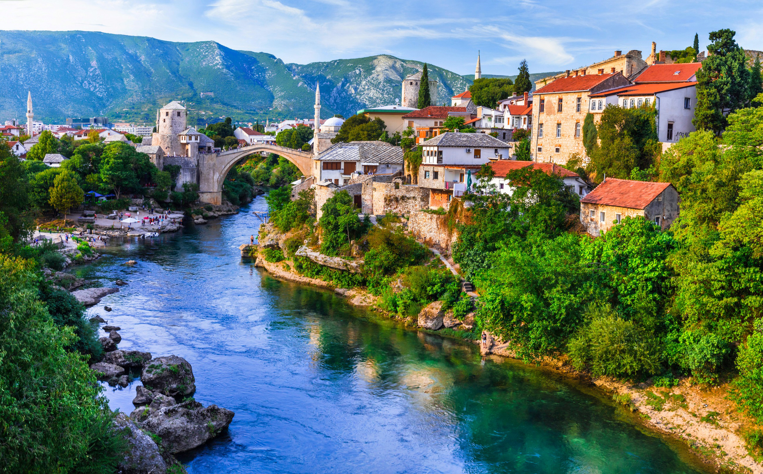 Resa till Bosnien och Hercegovina - Vy över den historiska stenbron Stari Most i Mostar, omgiven av traditionella byggnader och det klara vattnet i floden Neretva.