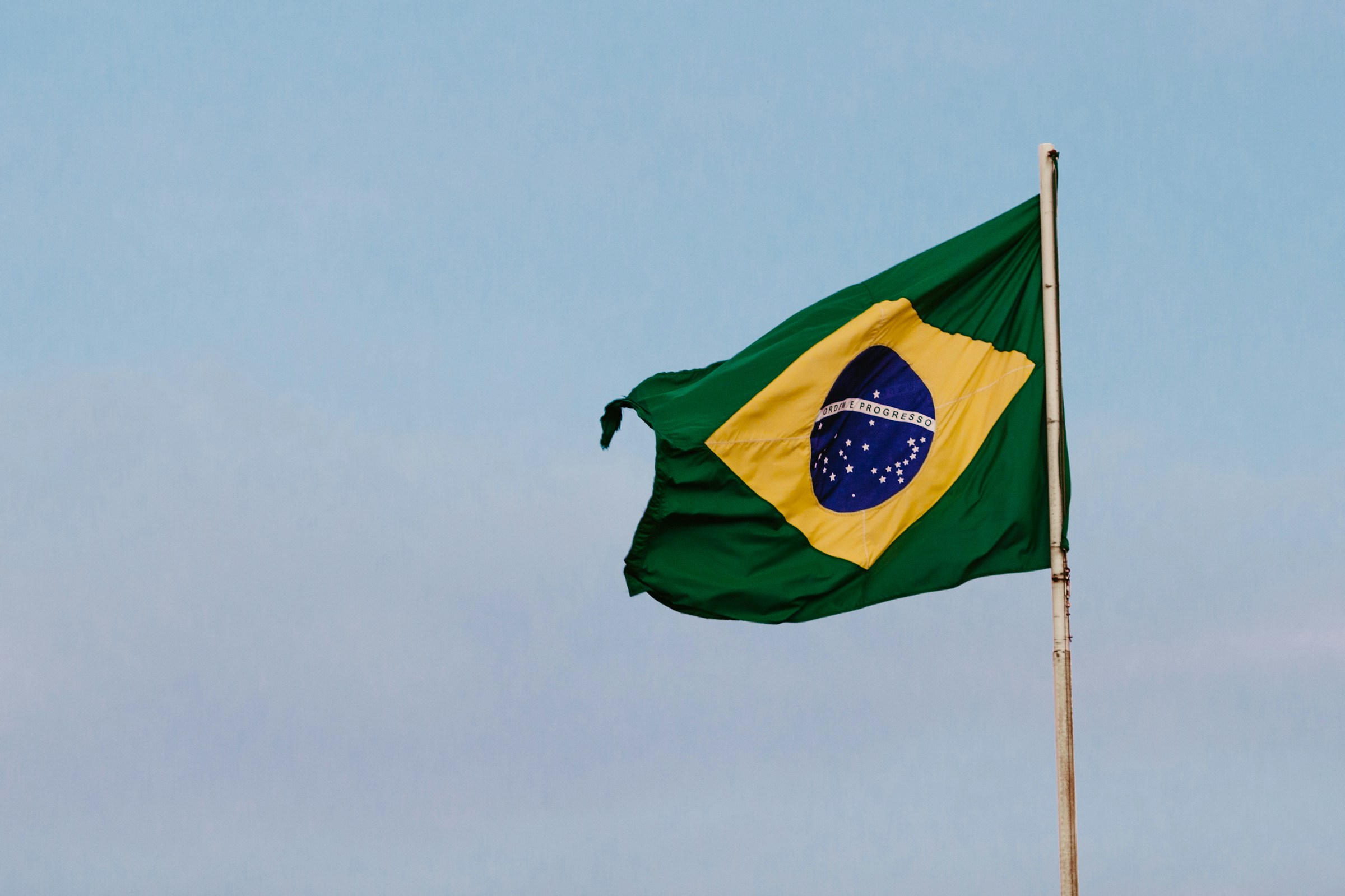 Brasilianska flaggan vajar mot en klar himmel.