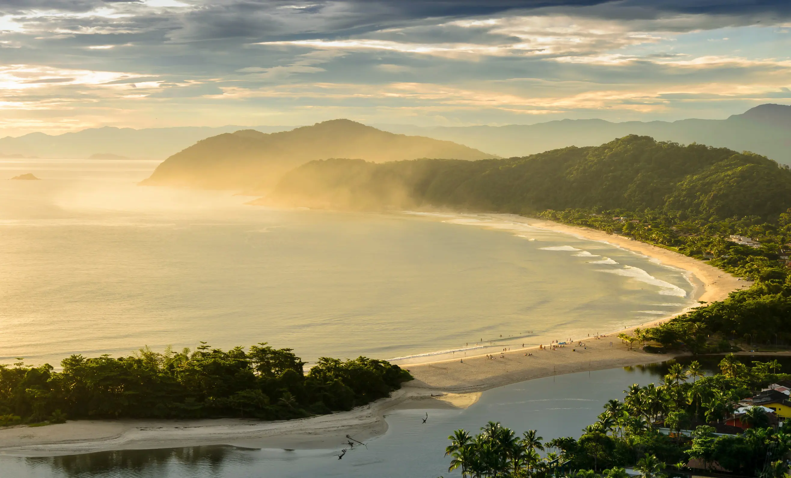 Resa till Brasilien - Soluppgång över naturskönt tropiskt strandlandskap med mjukt ljus och berg i bakgrunden.