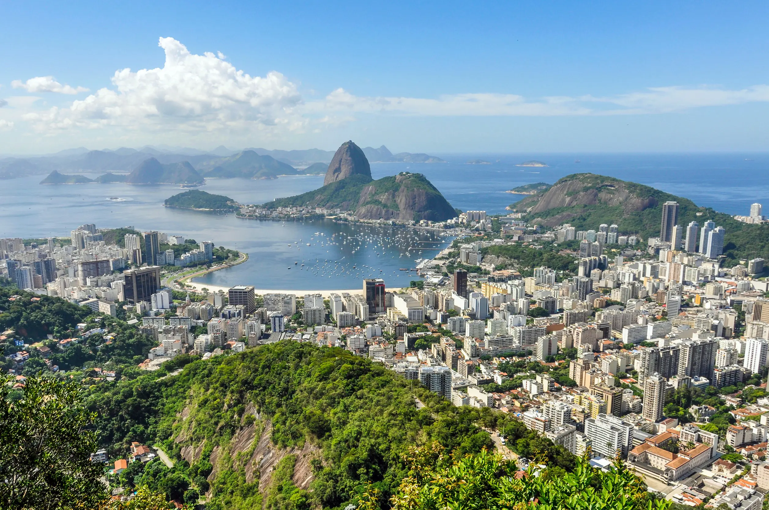 Resa till Rio de Janeiro - Panoramautsikt över Rio de Janeiro med Sugarloaf Mountain och Guanabara Bay, omgiven av stadsbebyggelse.