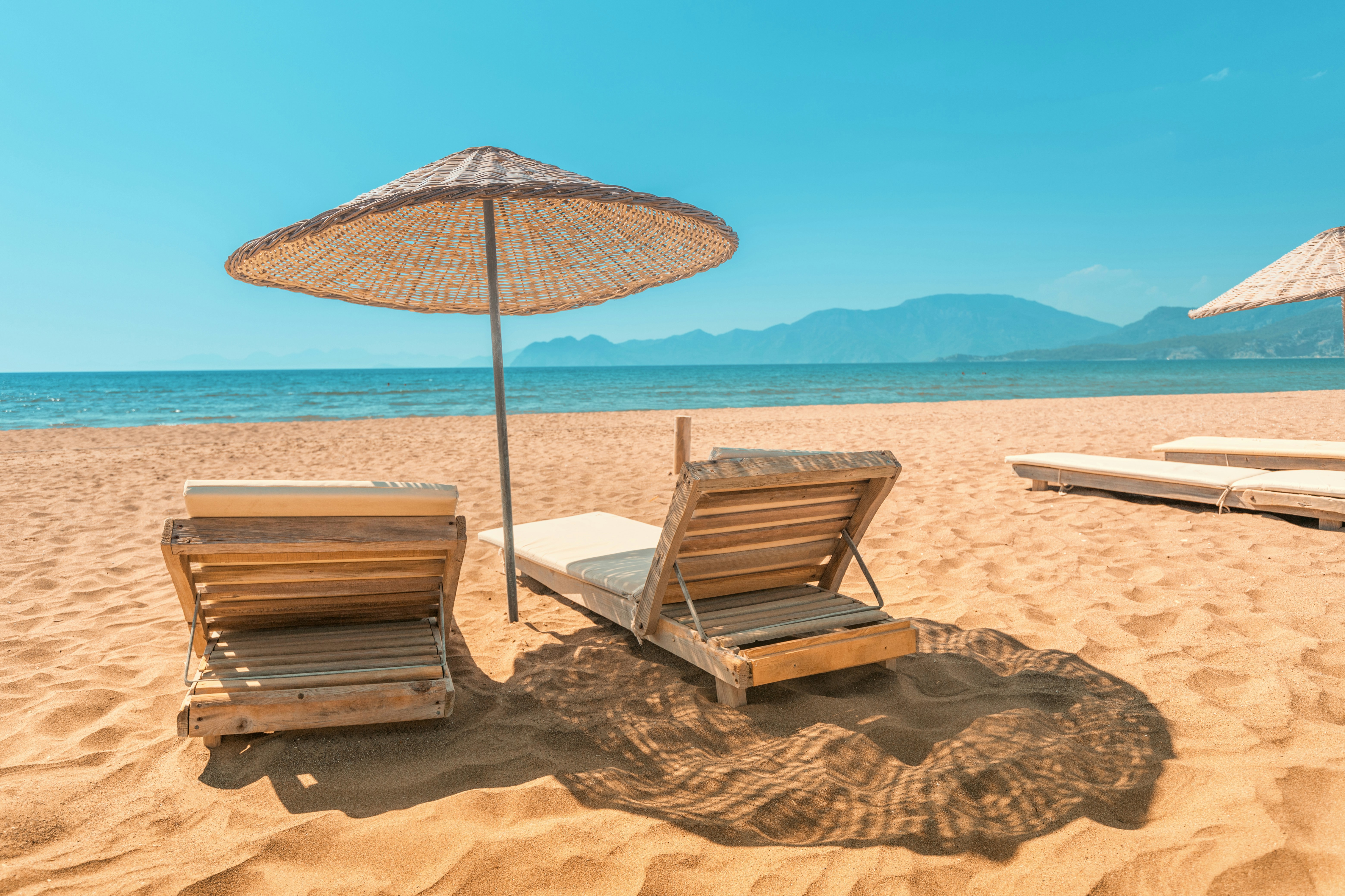 Solstolar och parasoll på stranden med berg och klar himmel i bakgrunden i Sunny Beach i Bulgarien.