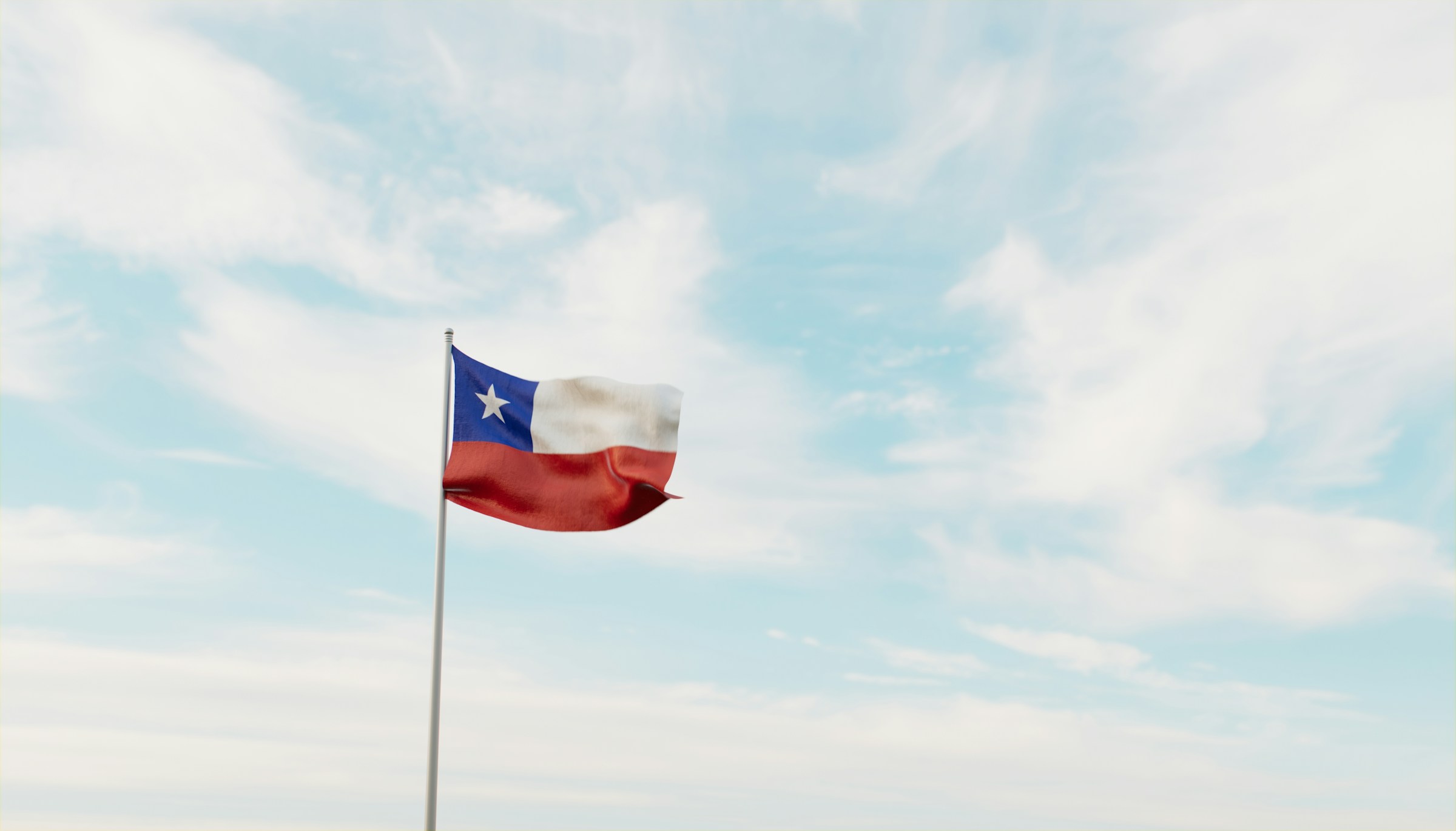 Chilenska flaggan vajar mot en klar himmel med lätta moln.