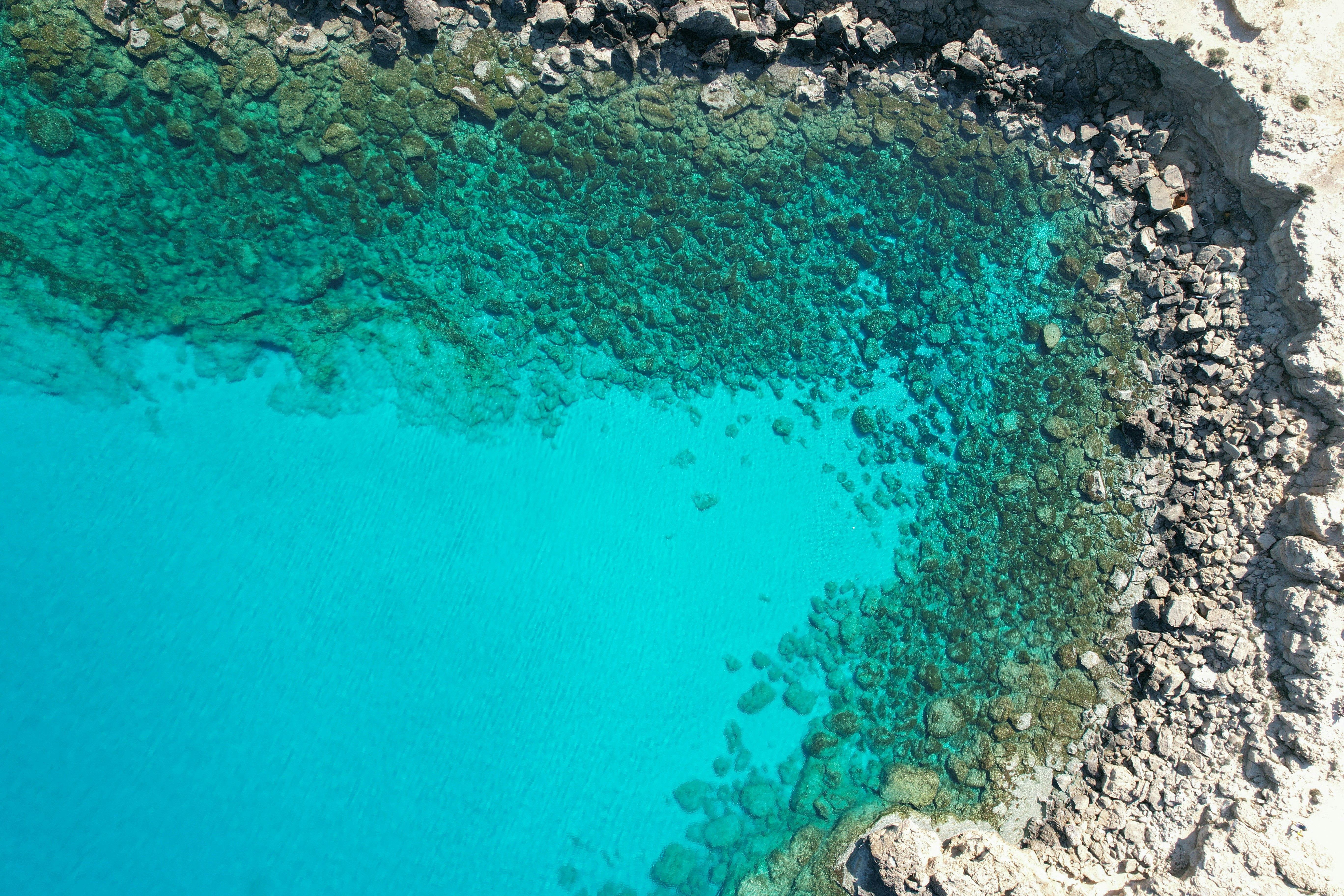 Flygfoto av kristallklart turkost vatten vid klippig kustlinje i Ayia Napa.