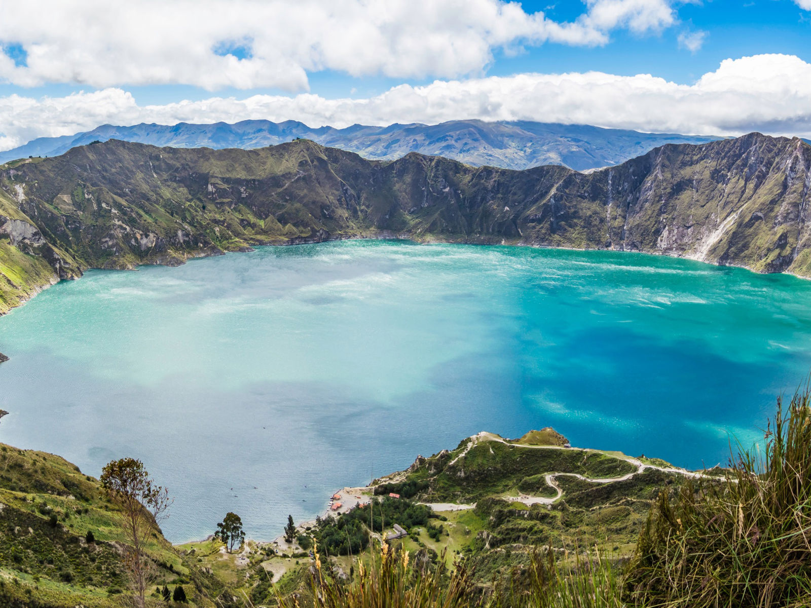 Resa till Ecuador - Bred panoramavy över Quilotoasjön i Ecuador med turkos vatten och bergslandskap.
