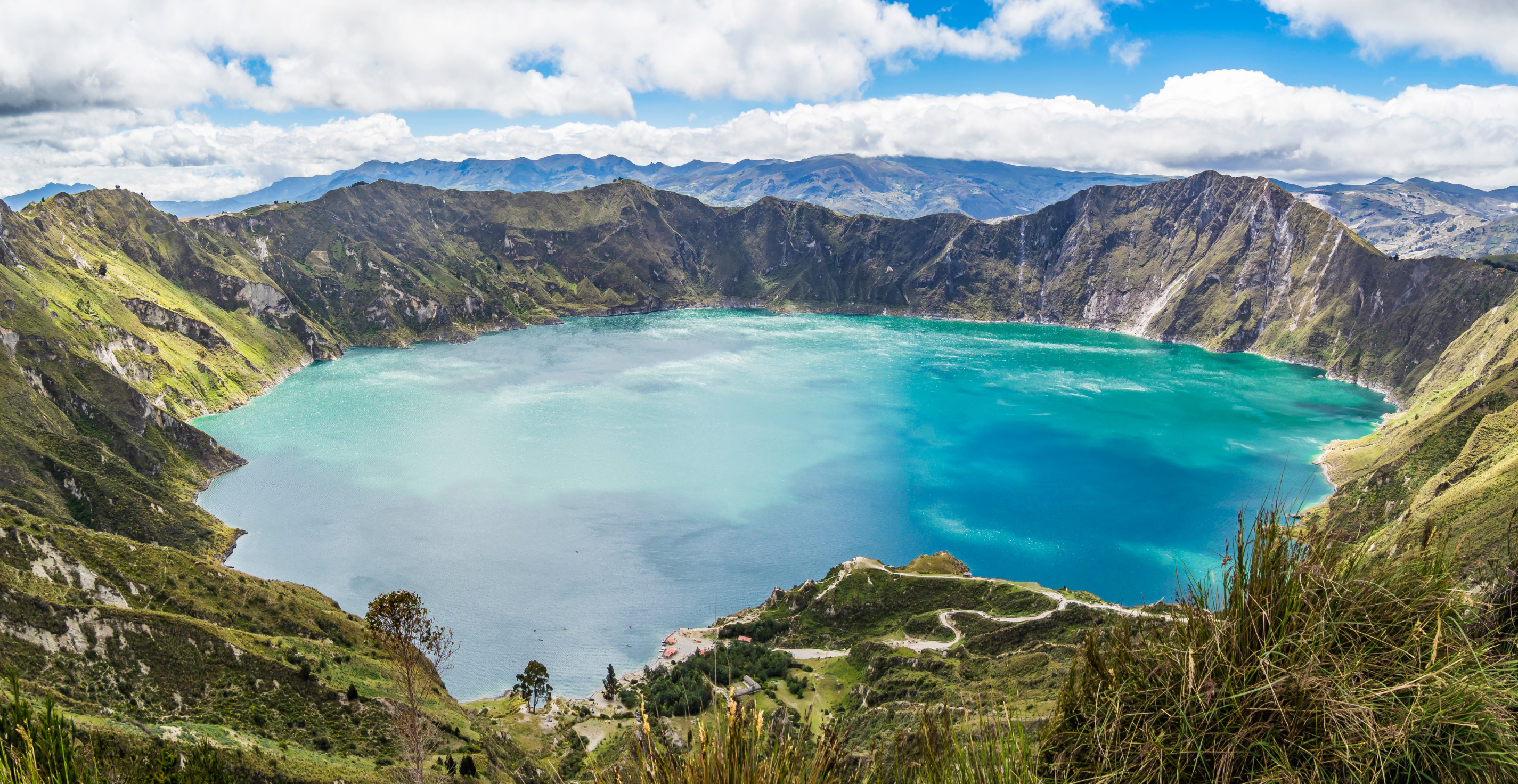 Resa till Ecuador - Bred panoramavy över Quilotoasjön i Ecuador med turkos vatten och bergslandskap.