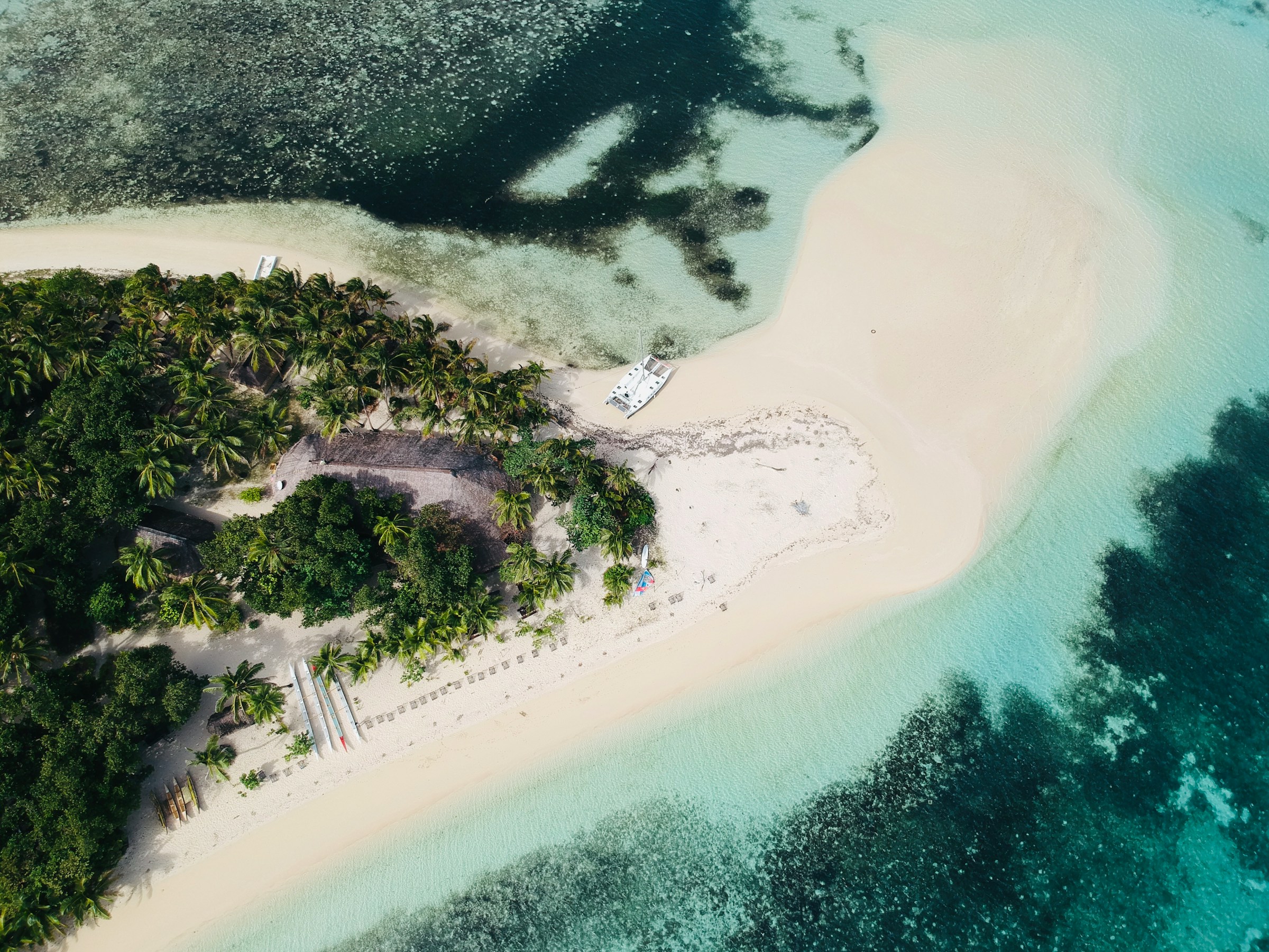 Flygfoto av tropiska Fiji med kristallklart vatten och vita sandstränder, omgiven av palmer.