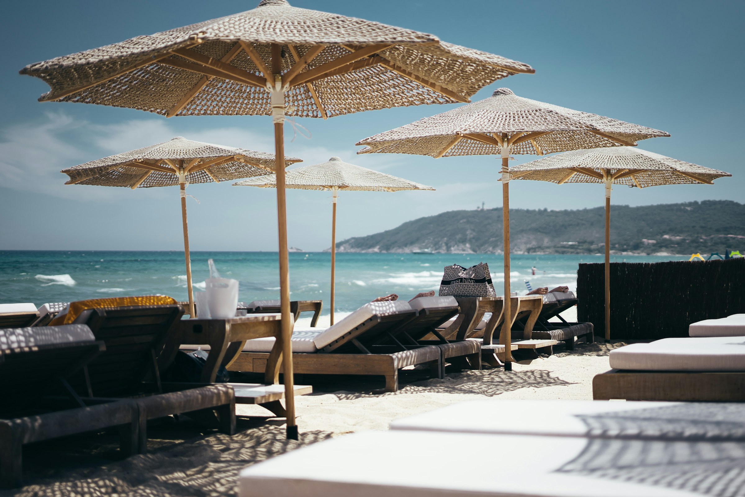 Strandparasoller och solstolar vid havet på en solig dag i Cannes.
