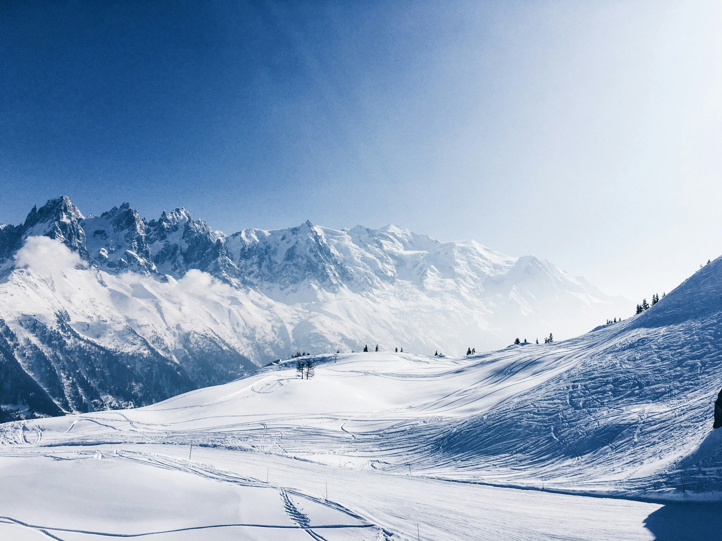 Vy över vinterland och snötäckta dalar och berg i Chamonix, Frankrike med blå himmel i bakgrunden