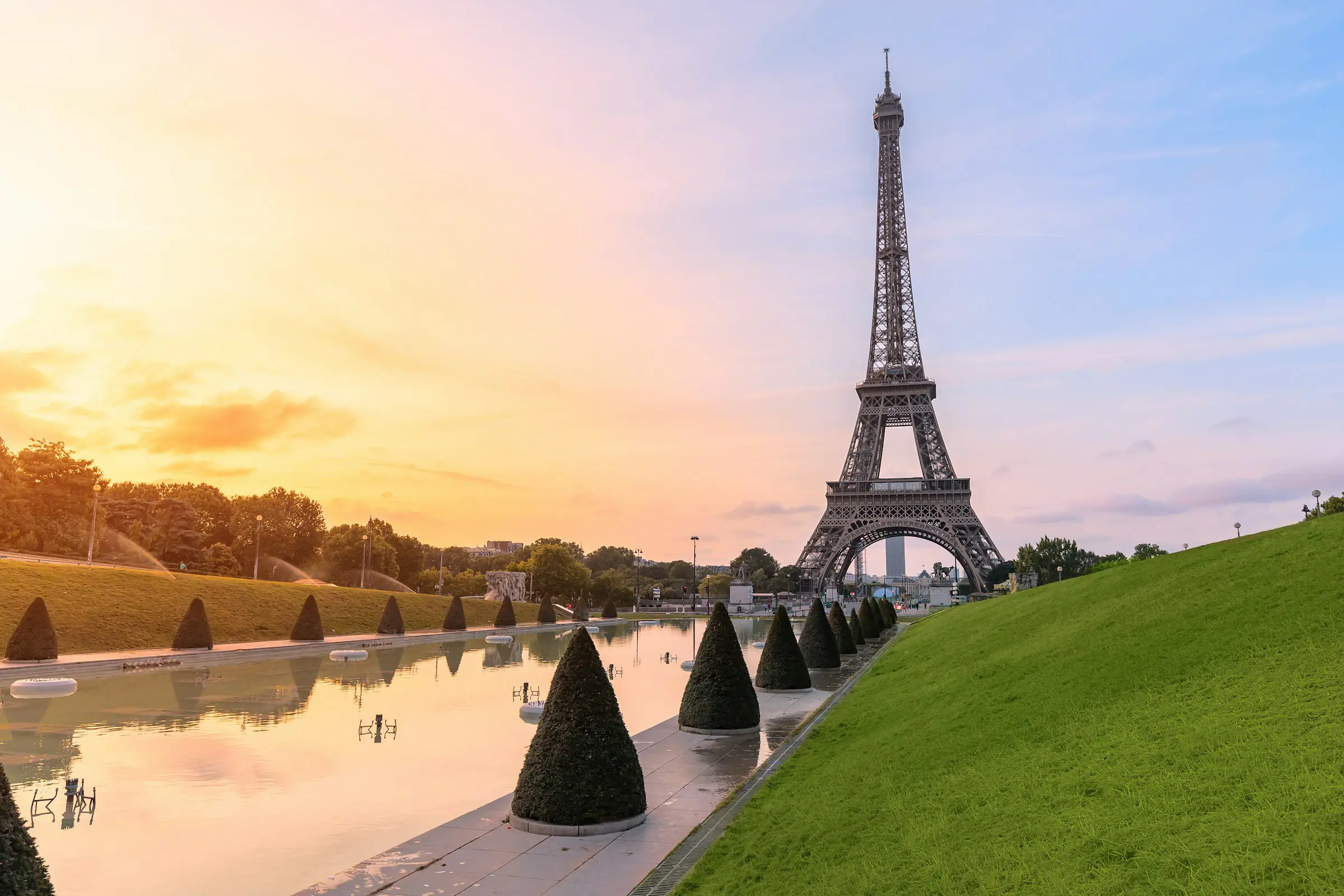 Resa till Paris - Eiffeltornet i Paris vid solnedgång med kontrastrik himmel och reflekterande vatten.