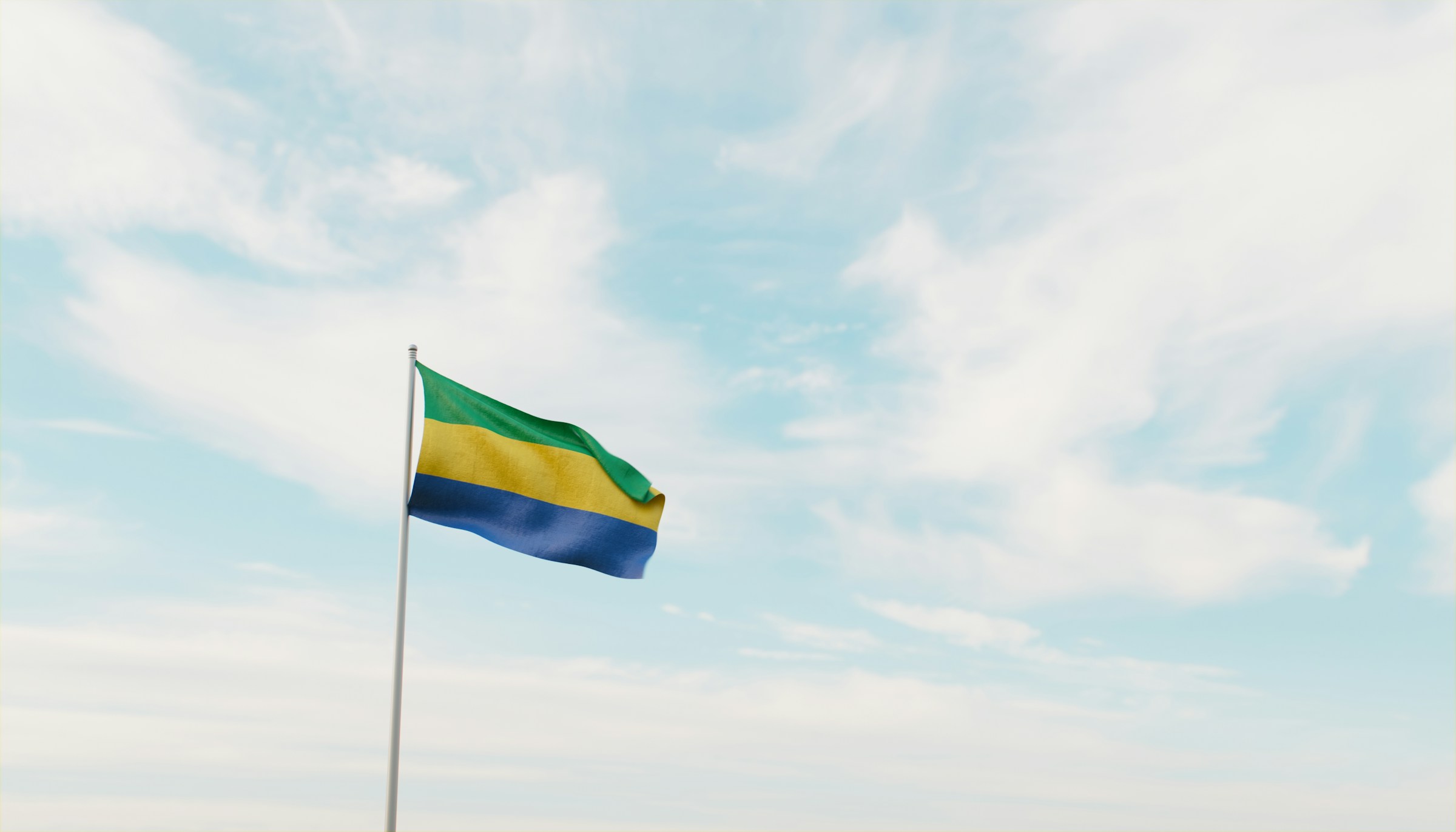 Gabons flagg vajar mot en klarblå himmel med lätta moln.