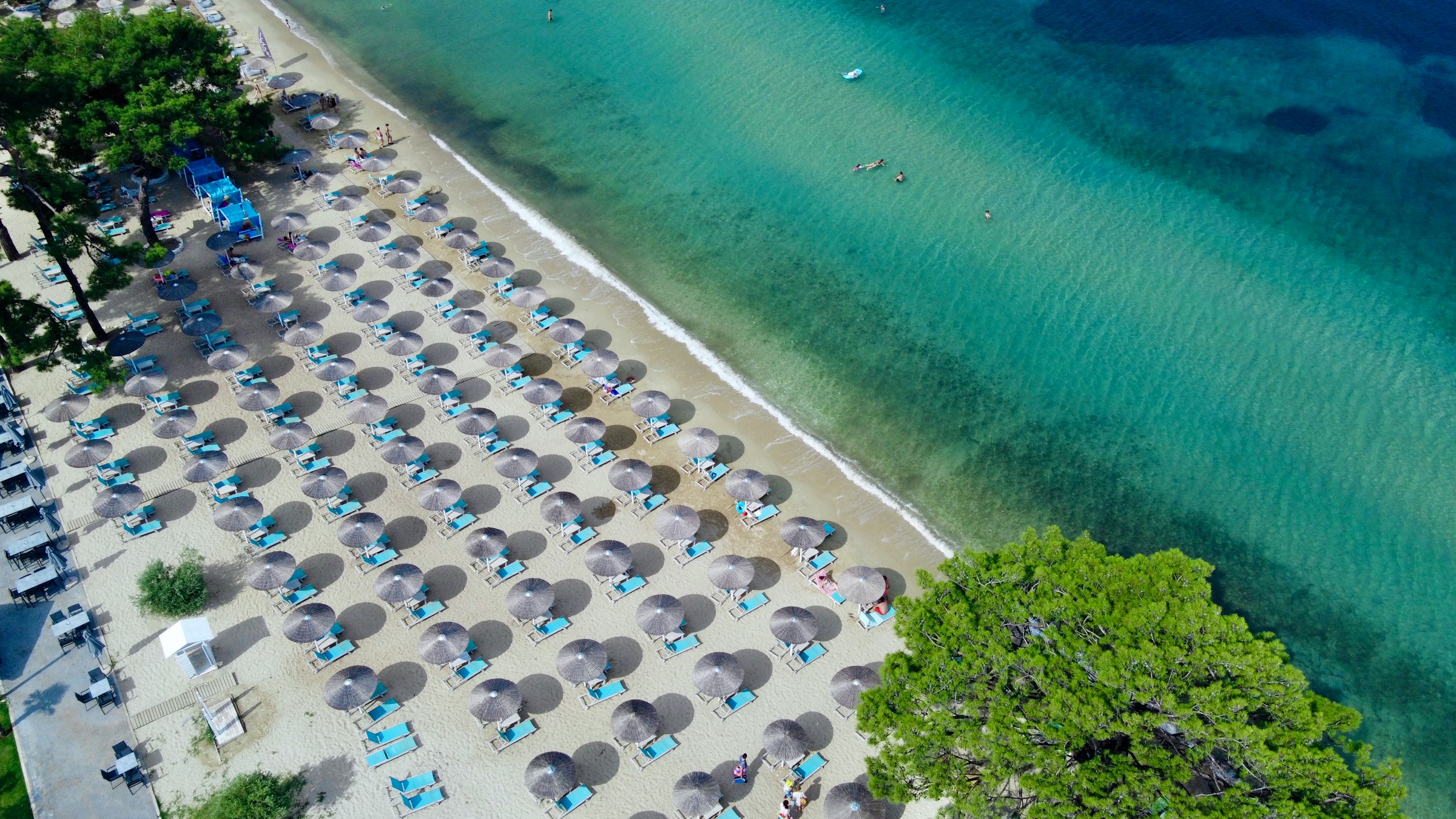 Lugn och attraktiv strandvy med parasoller och klart vatten från ovan i Thassos, Grekland