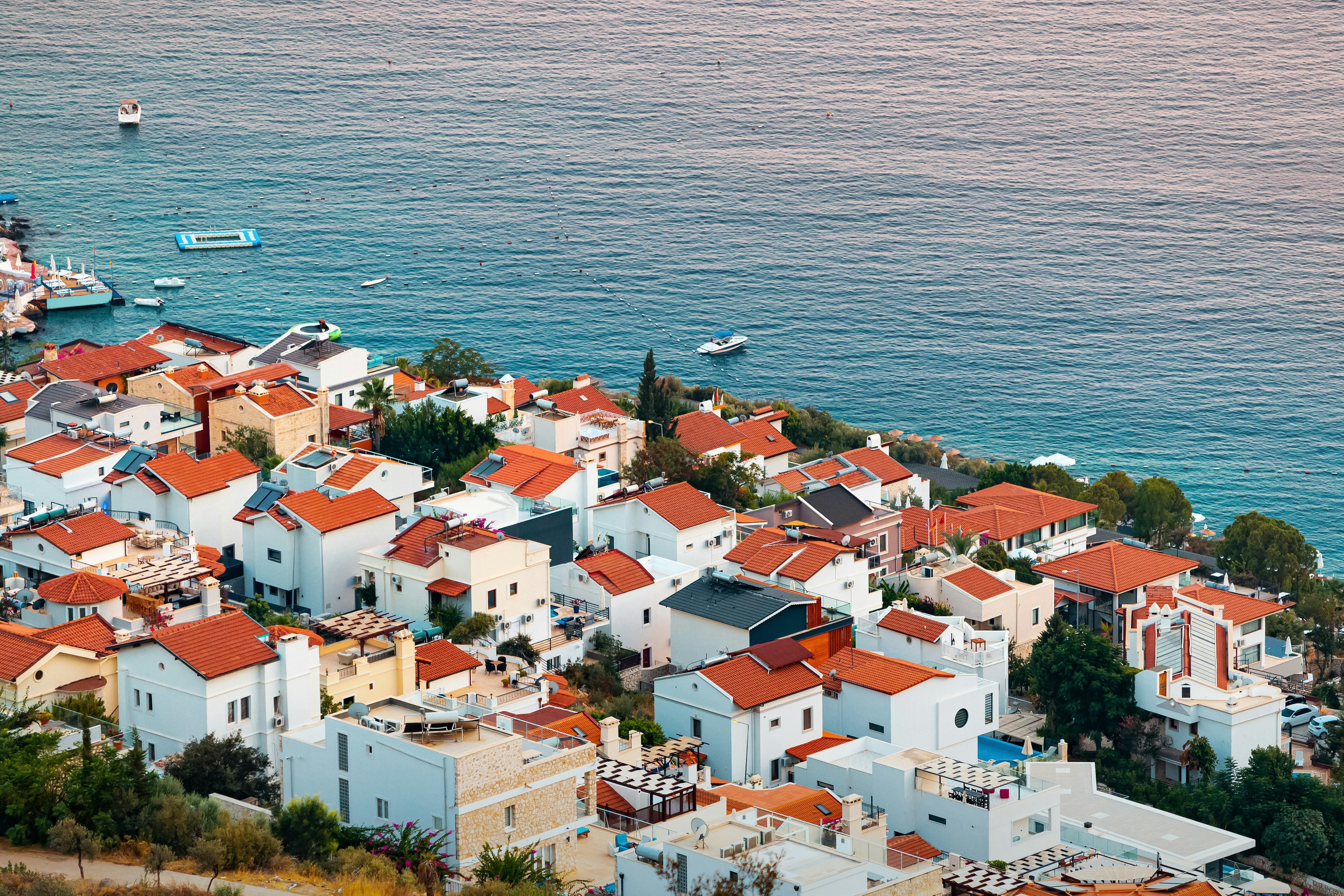 Vy över kuststad med vita hus och röda tak vid havet i skymningsljus på Skiathos