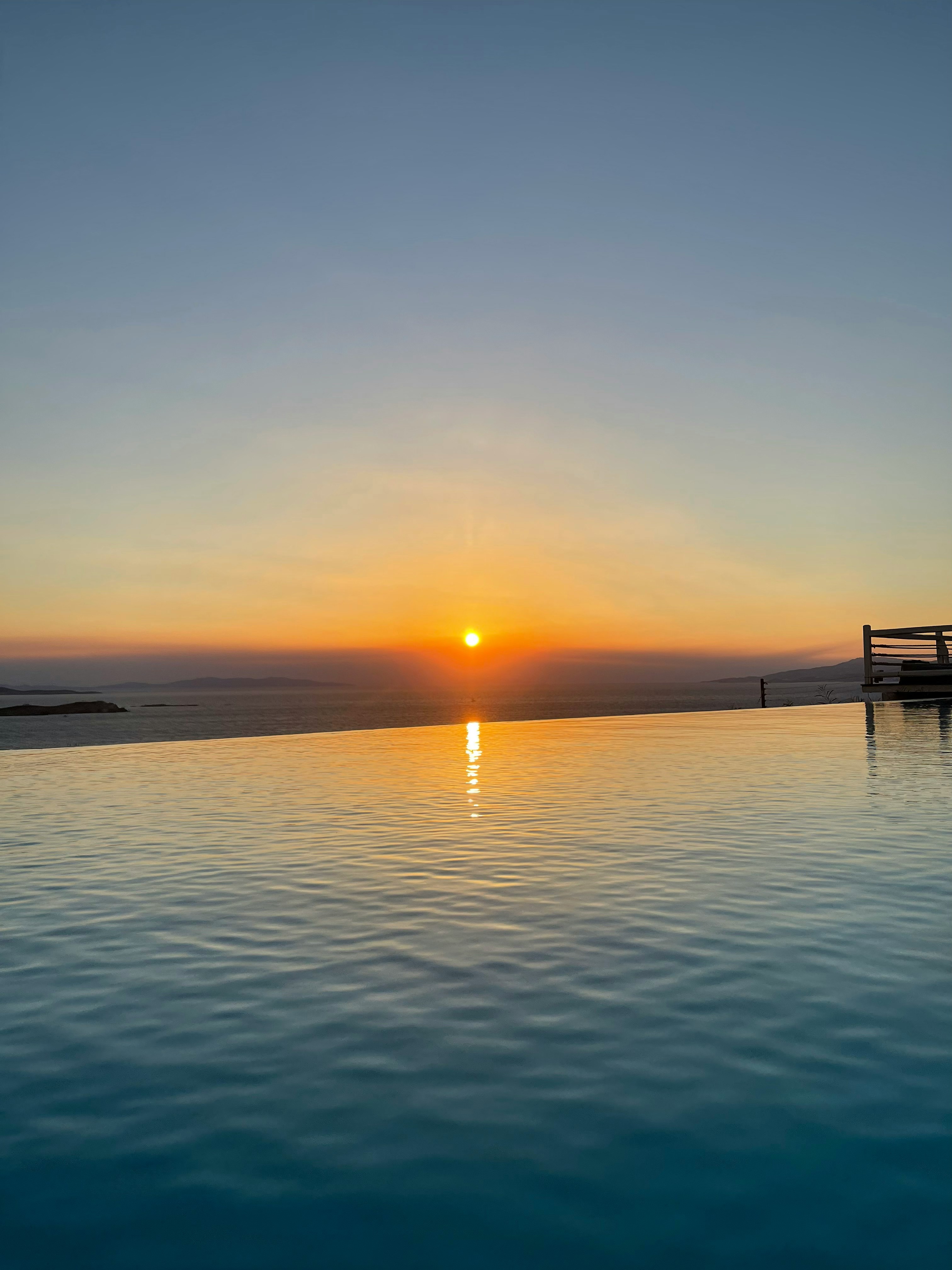 Solnedgång vid infinity-pool med reflektion över vattnet och klart himmel i Thessaloniki