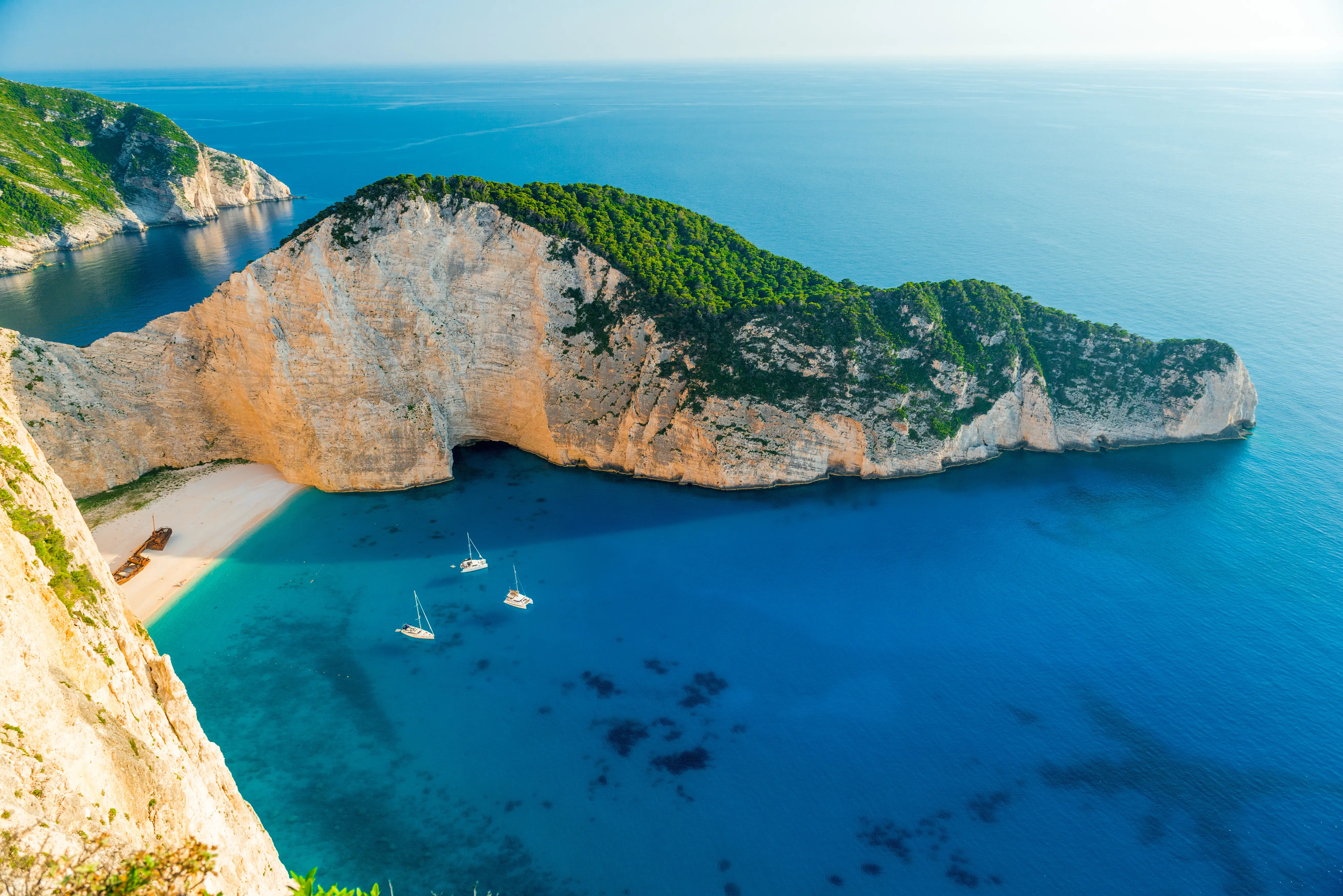 Resa till Zakynthos - Panoramautsikt över en idyllisk bukt med kristallklart turkost vatten, vita segelbåtar och en strandslinga omgiven av branta klippor