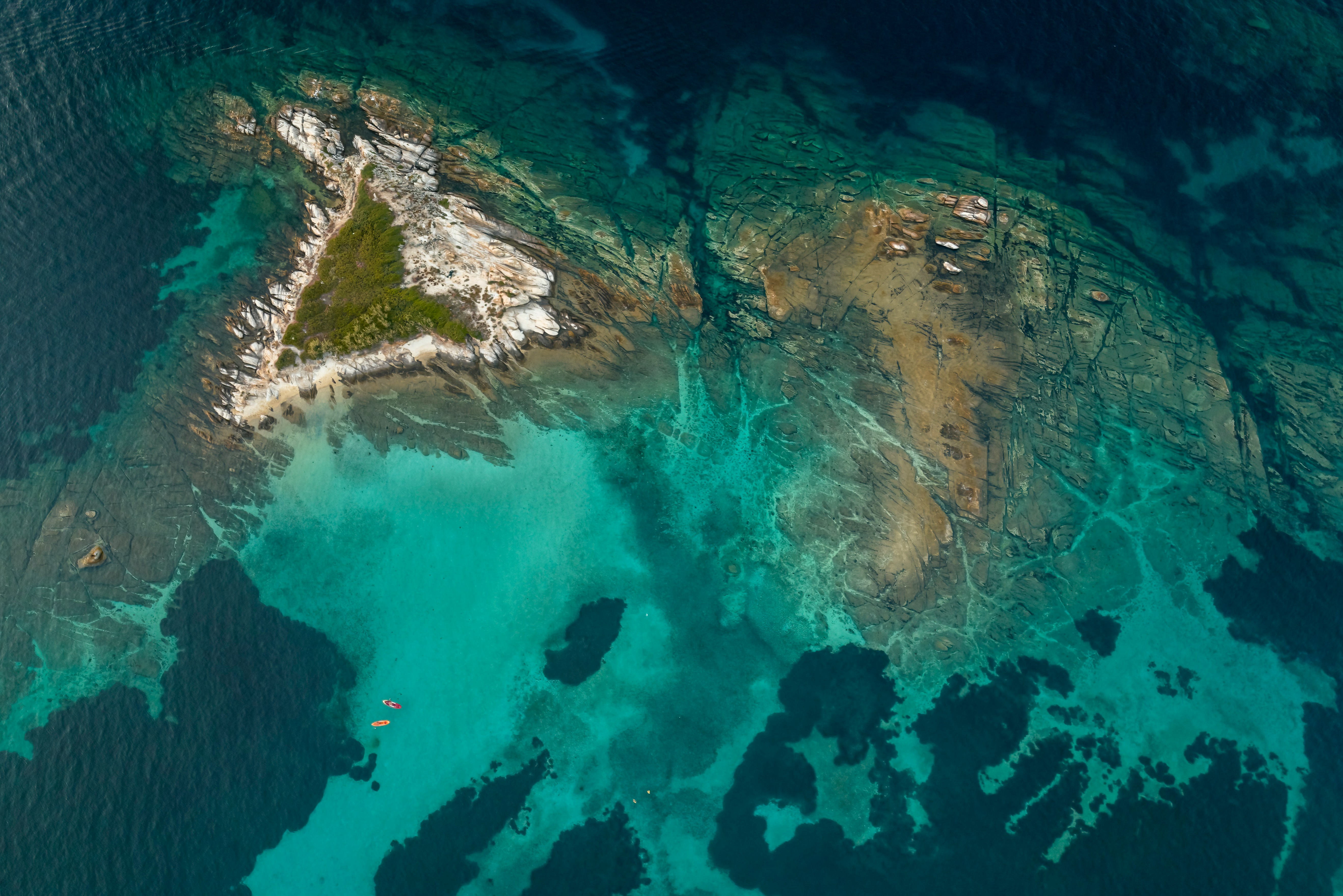 Flygbild av en liten ö med turkos vatten och klippiga strukturer omgiven av korallrev i Haiti