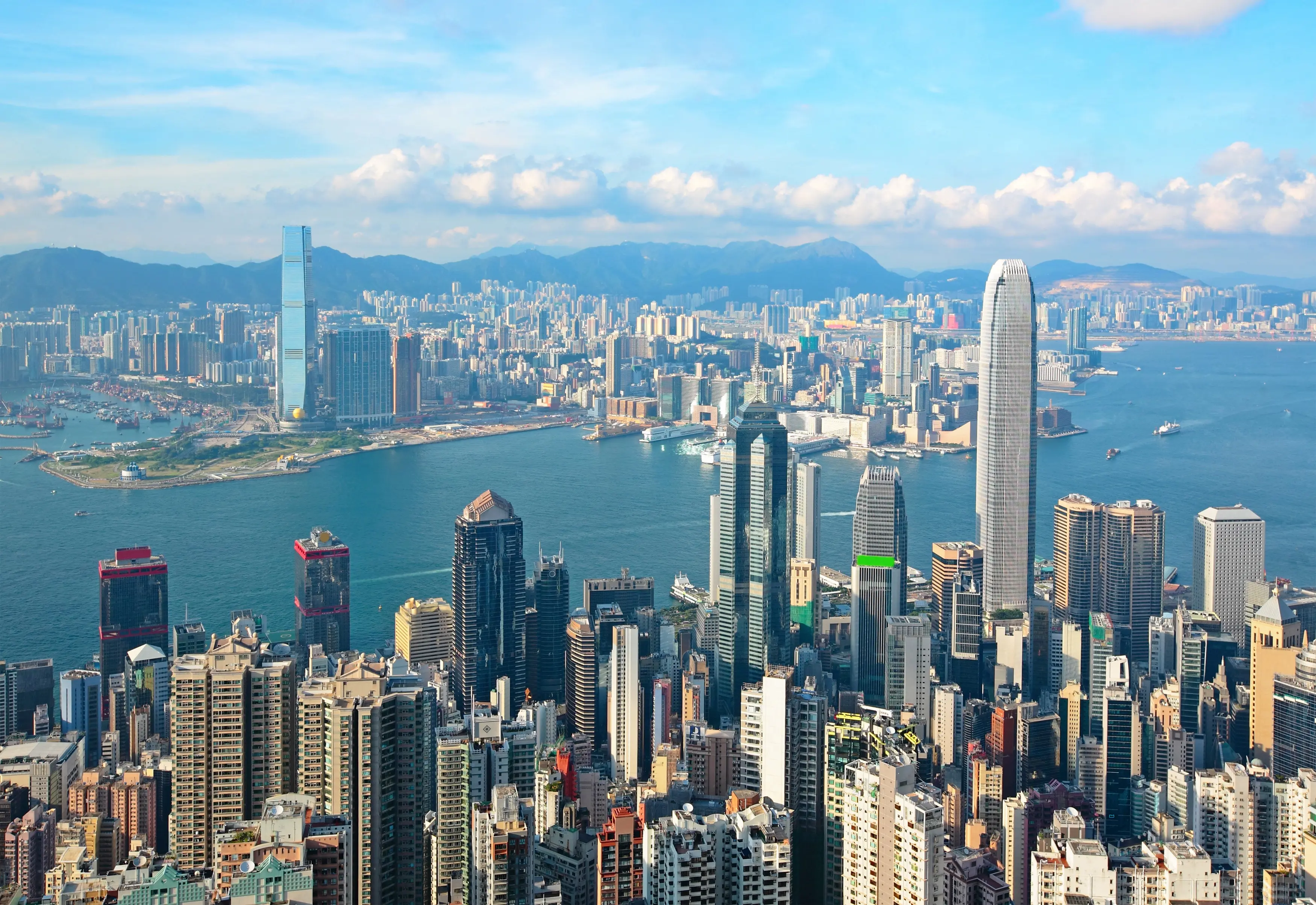 Resa till Honkong - Panoramautsikt över Hongkongs stadssilhuett och Victoriahamnen under dagen med blå himmel.