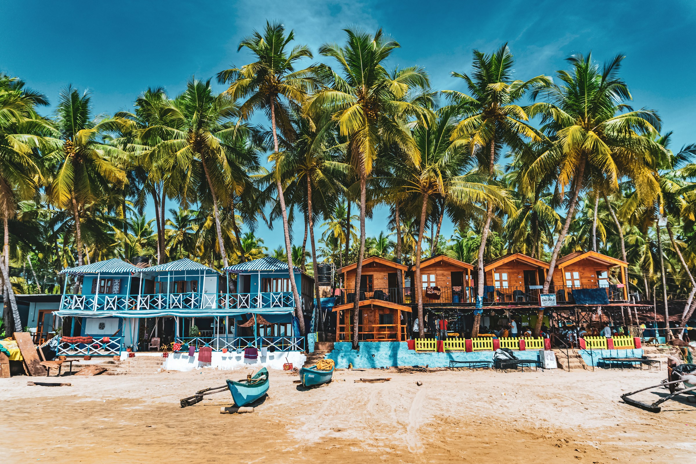 Färgglada strandhyddor omgivna av palmer på en tropisk strand i Goa.