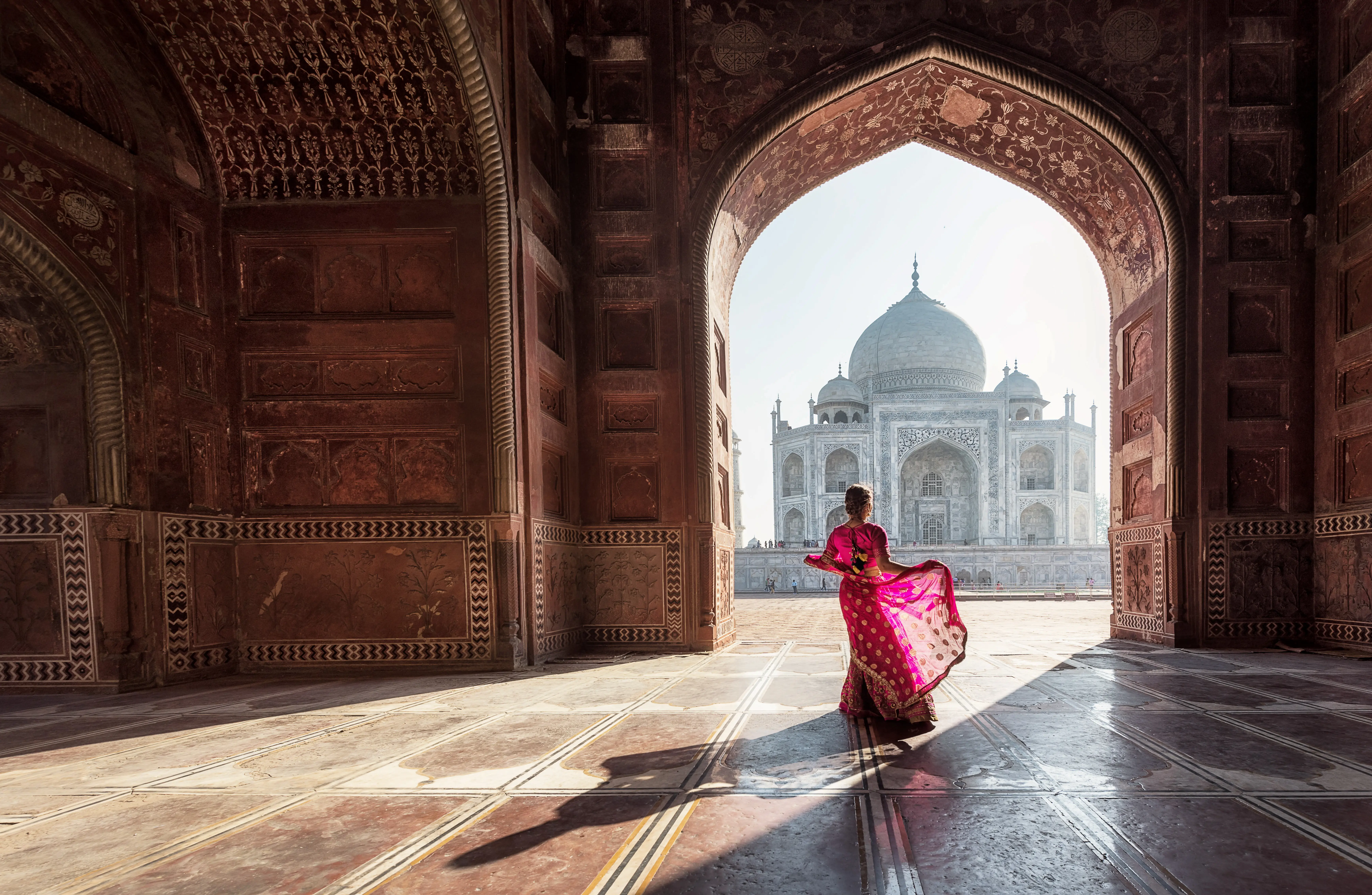 Resa till Indien - Kvinna i färgglad saree ser på Taj Mahal genom en bågformad ingång, Agra, Indien.