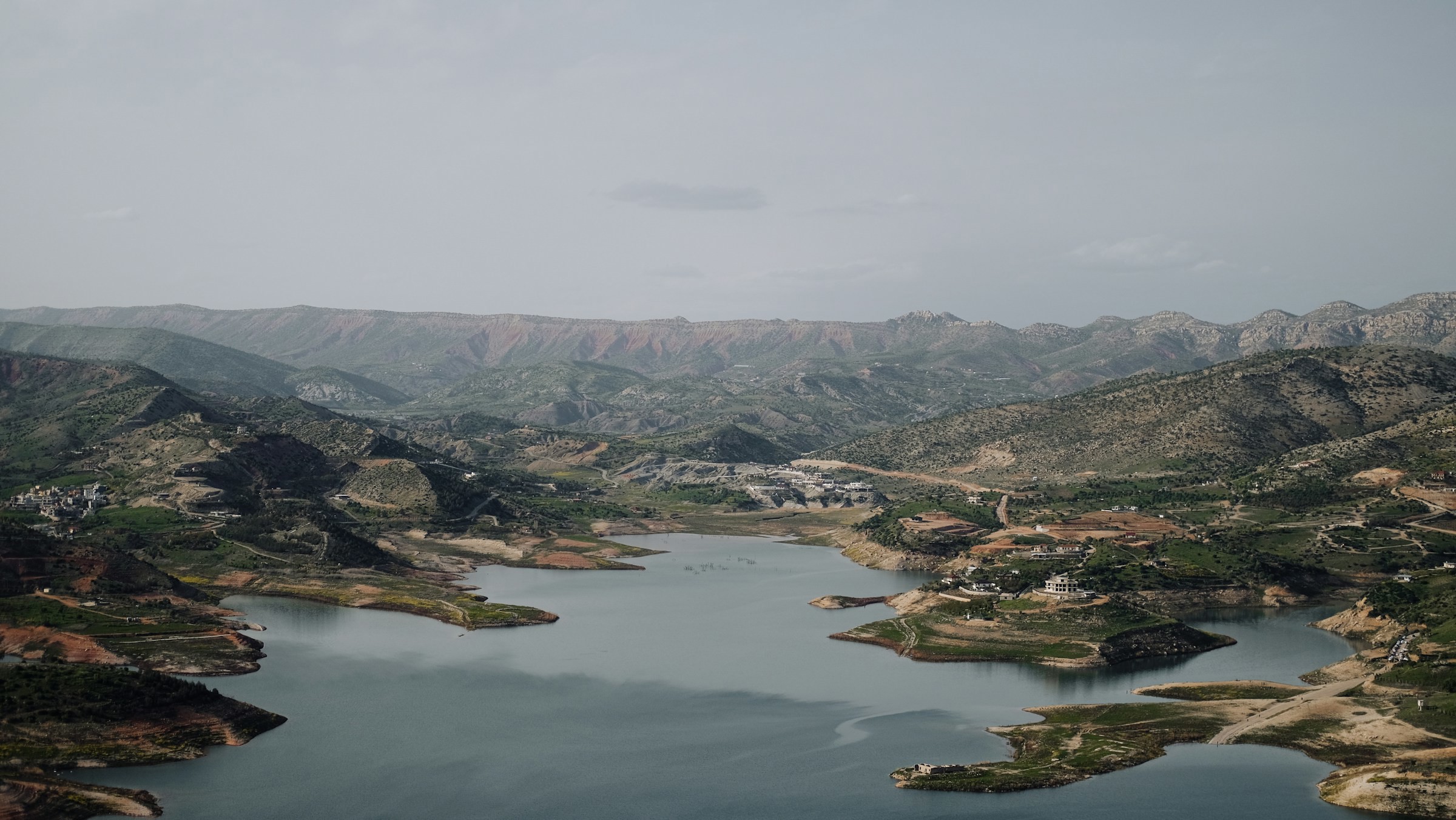 Bergslandskap vid sjö i dämpade färger, naturvy med kullar och vatten i Irak