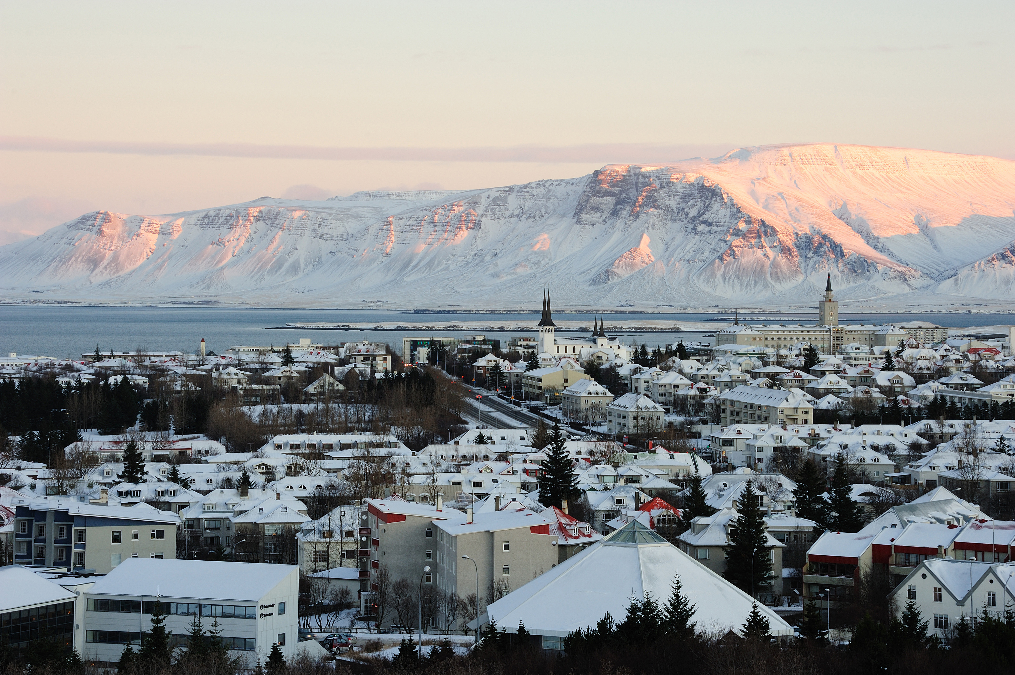 Resa till Reykjavik - Vy över Reykjavik stad med berg i bakgrunden i en solnedgång