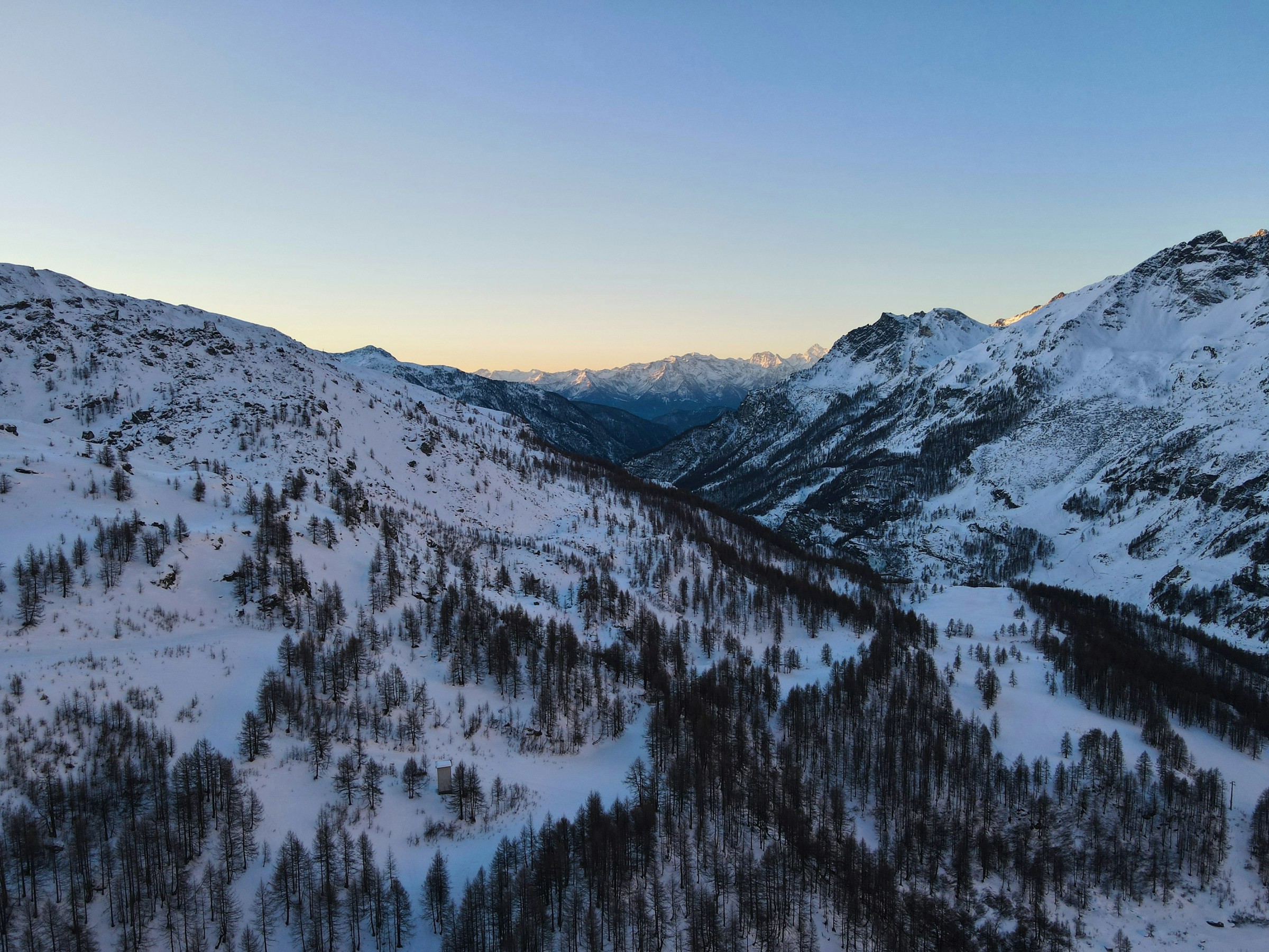 Vinterlandskap vid solnedgång med snötäckta berg och skog i alpin miljö i Cervinia.