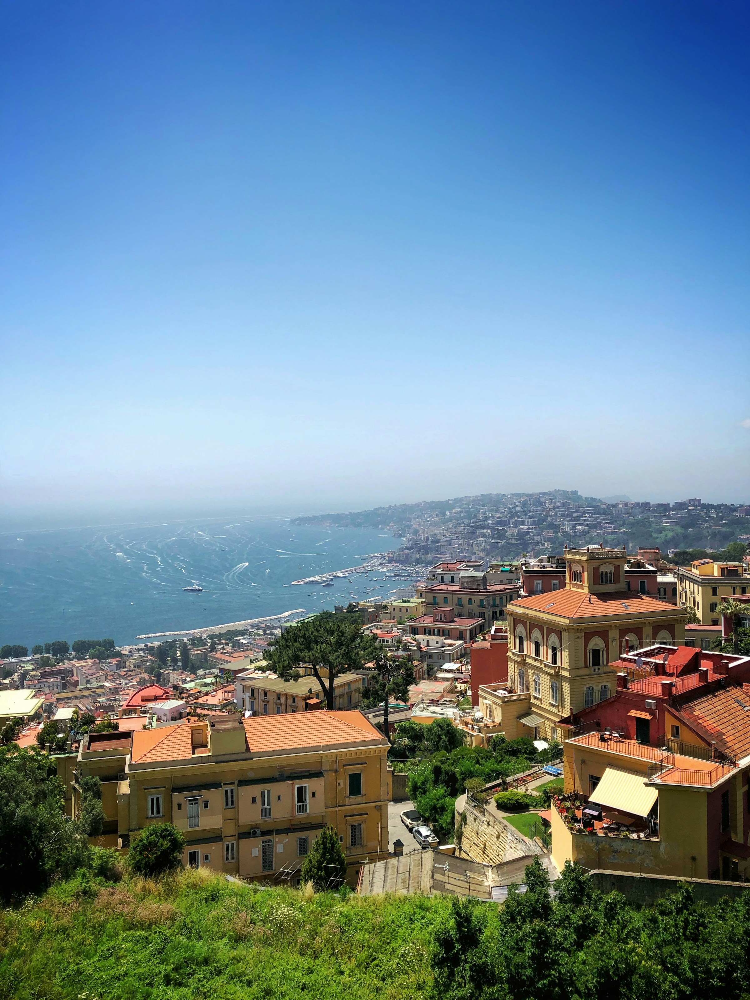 Utsikt över Neapel med traditionell arkitektur och blått hav under klar himmel i Italien.