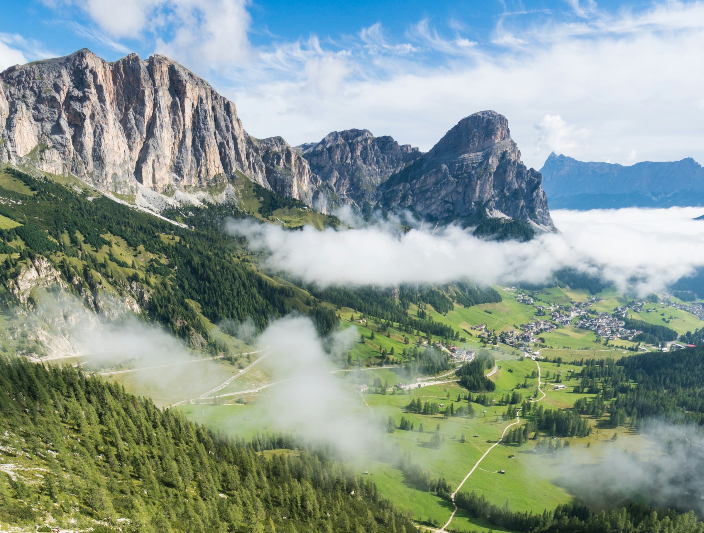 Beautiful view of lush valley and slopes with winter mountains and blue sky in the background