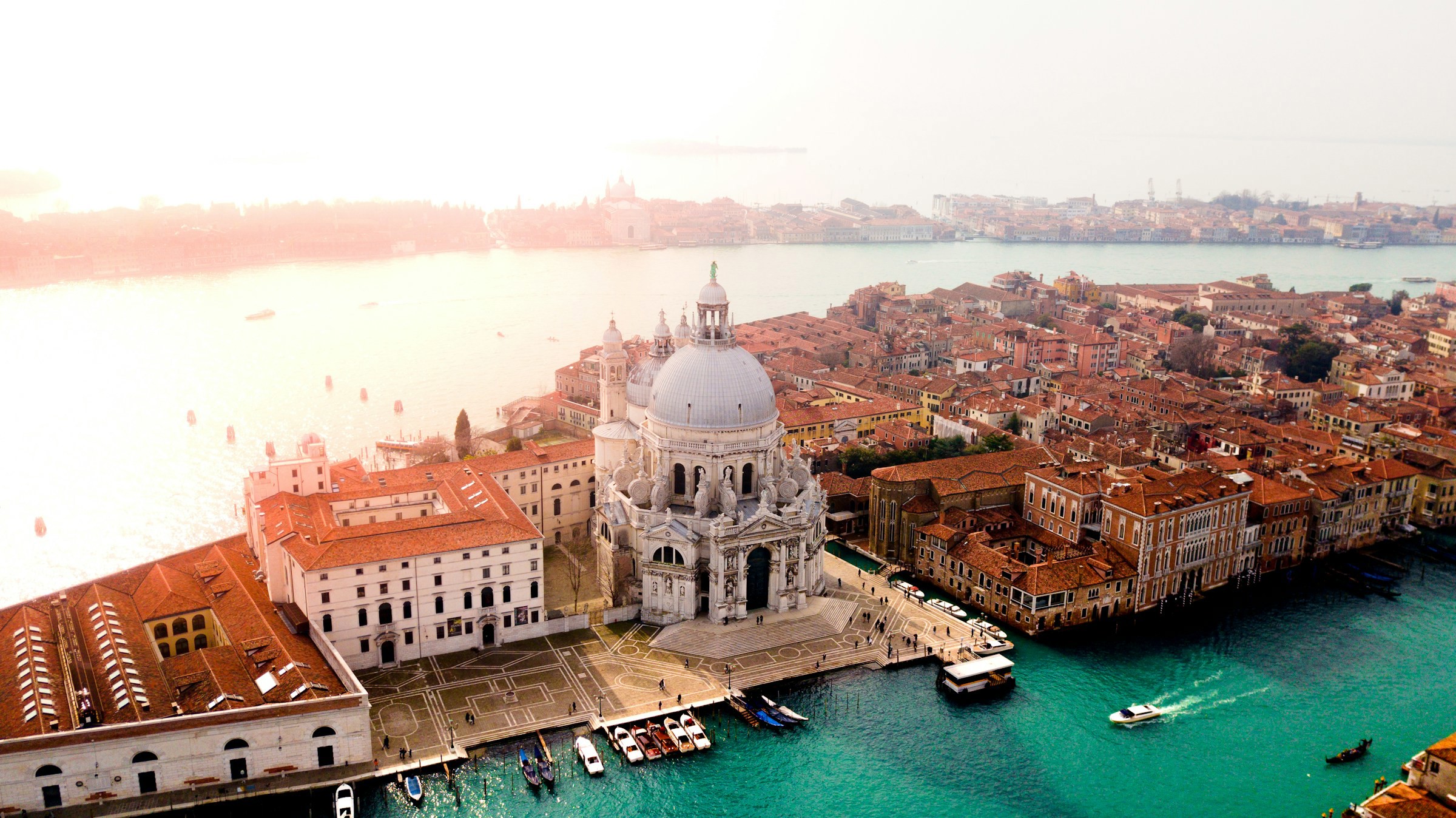 Flygbild över Basilica di Santa Maria della Salute och Canal Grande i Venedig vid solnedgången.