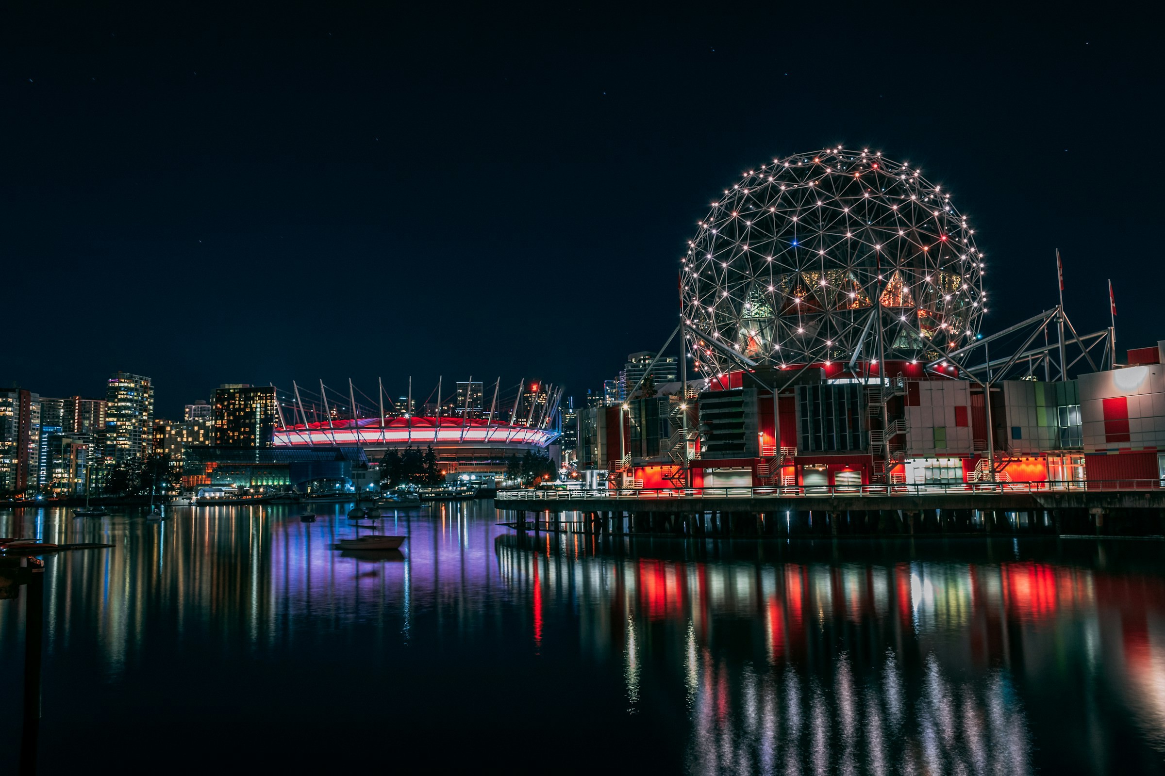 Vy över hamn i Vancouver under nattetid med stadsbelysning och neon ljus i bakgrunden