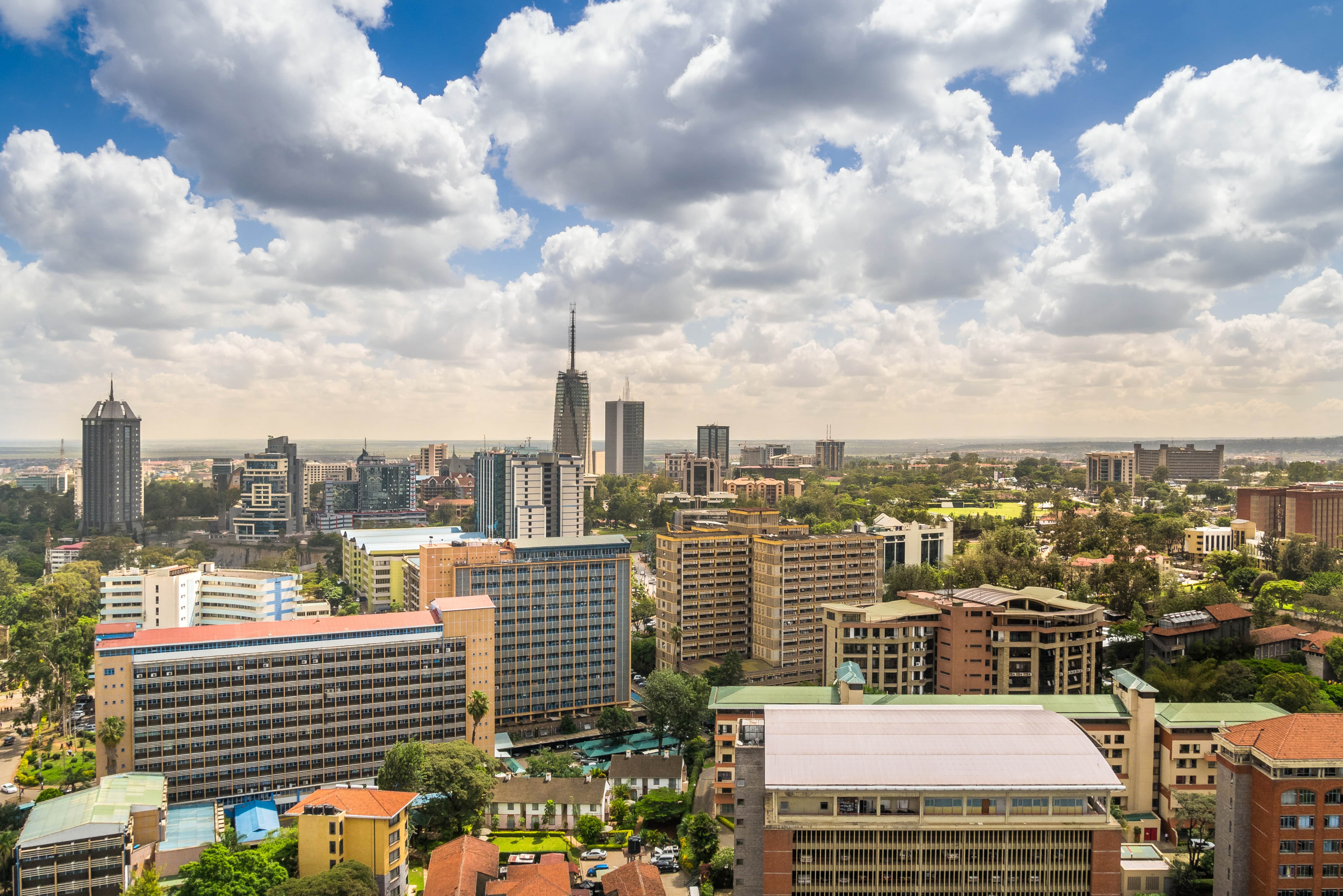 Travel to Nairobi - View of Nairobi city with several buildings, skyscrapers and greenery all around that meet a blue sky