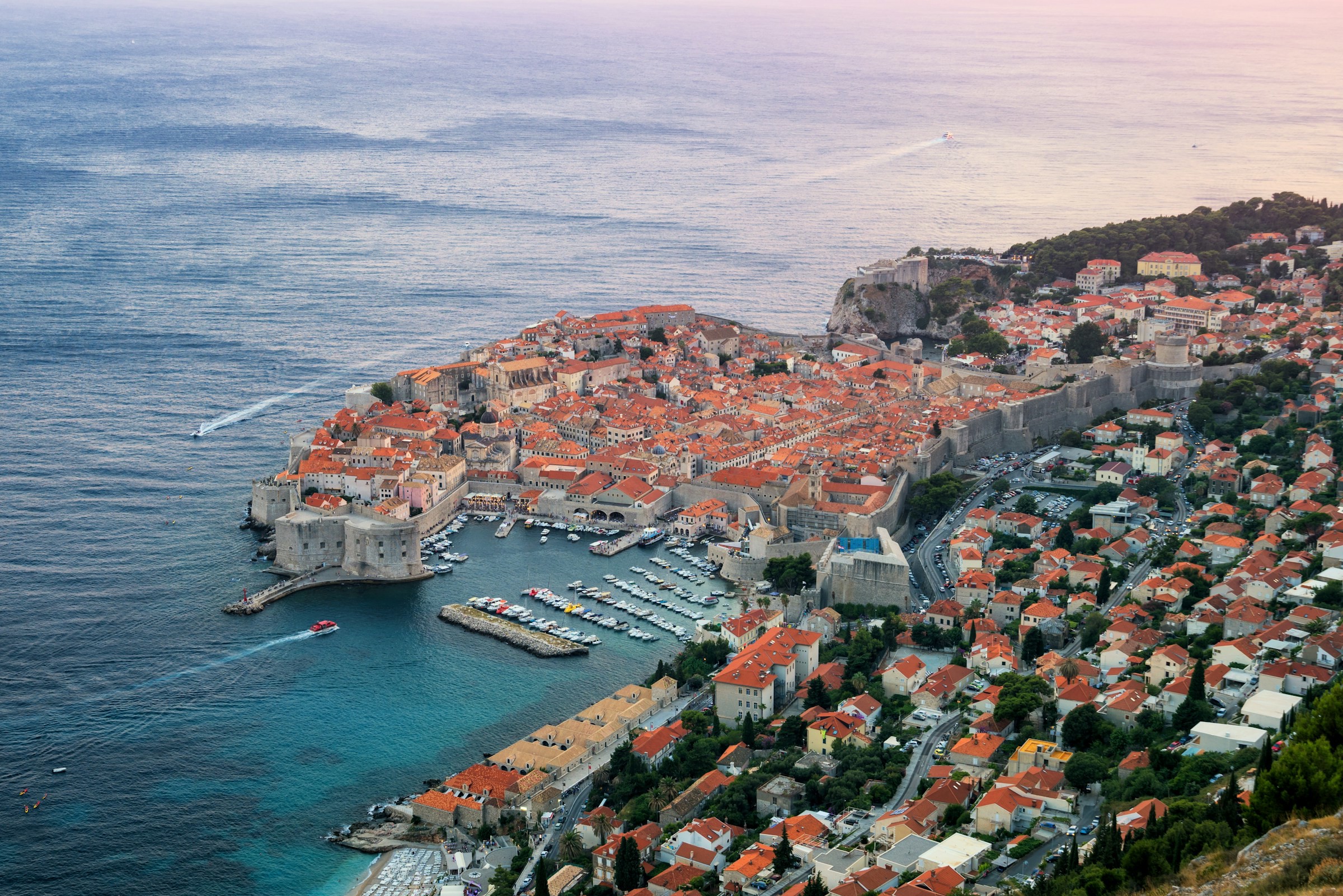 Panoramavy över hamnen i Dubrovnik som leder fram till staden och alla byggnader med blått hav och himmel i bakgrunden