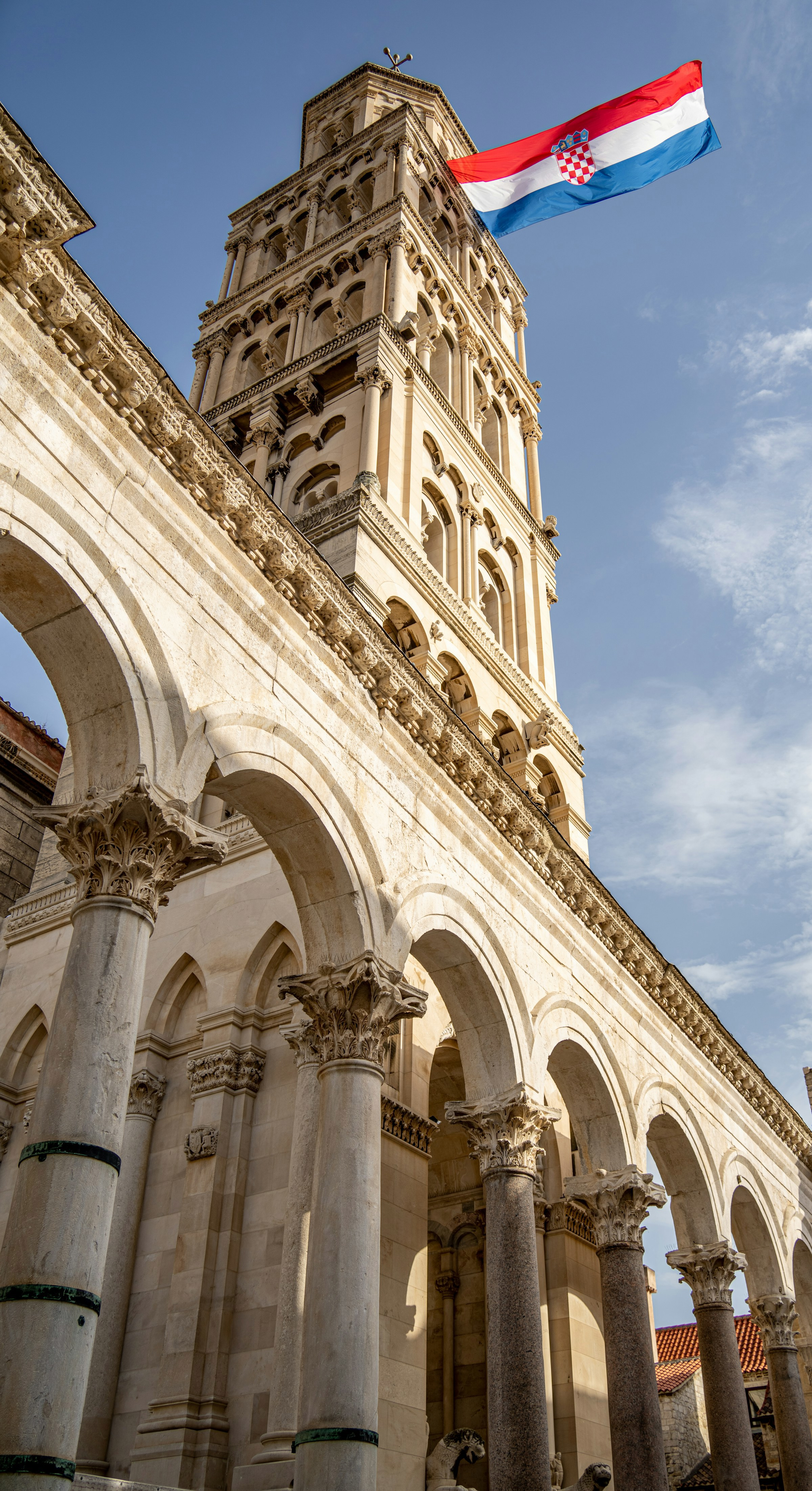 Diokletianus palats torn i Split, Kroatien, med den kroatiska flaggan fladdrande mot blå himmel.