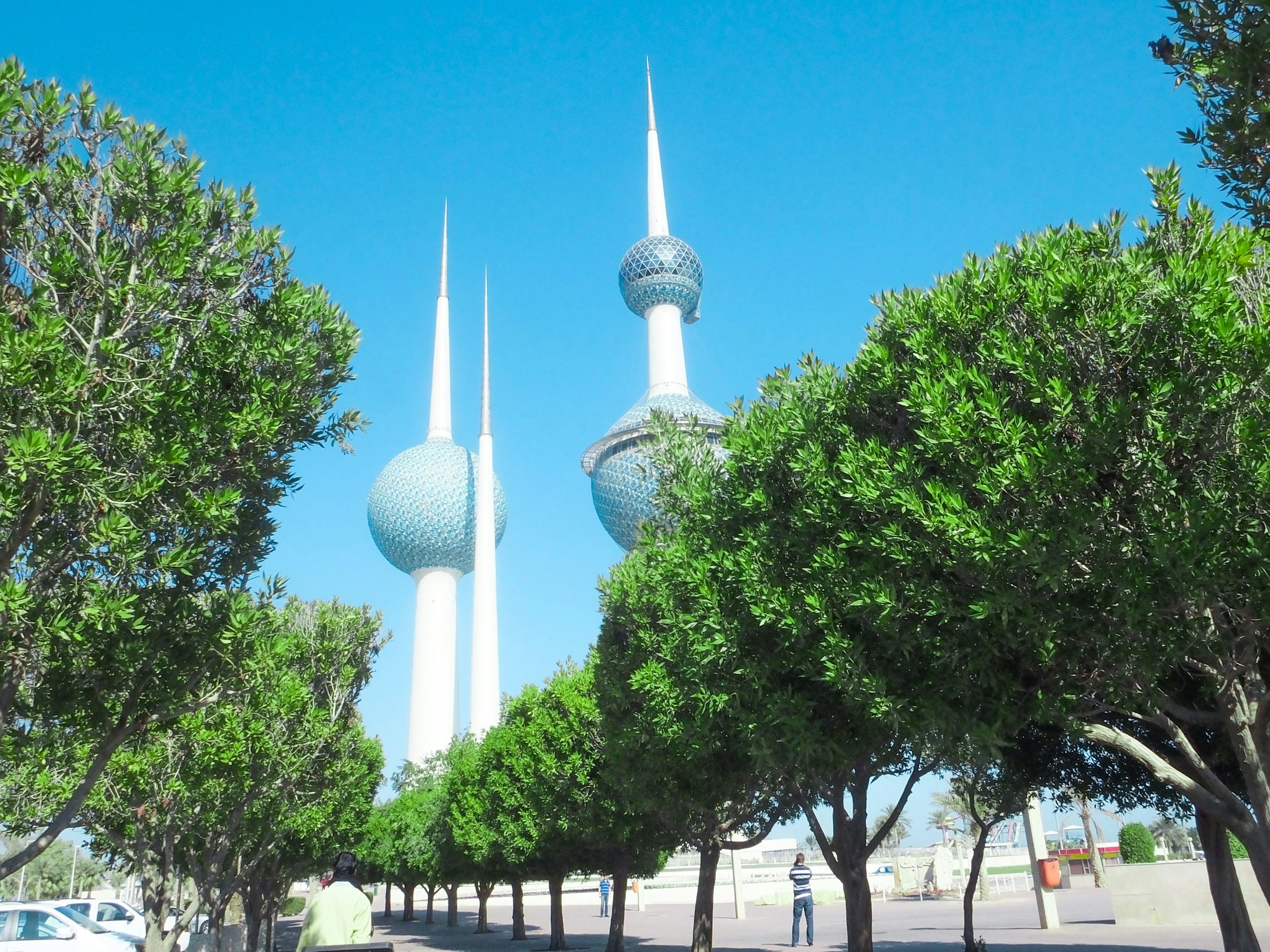 Vy underifrån på Kuwait Towers med grönska och träd runtomkring sig