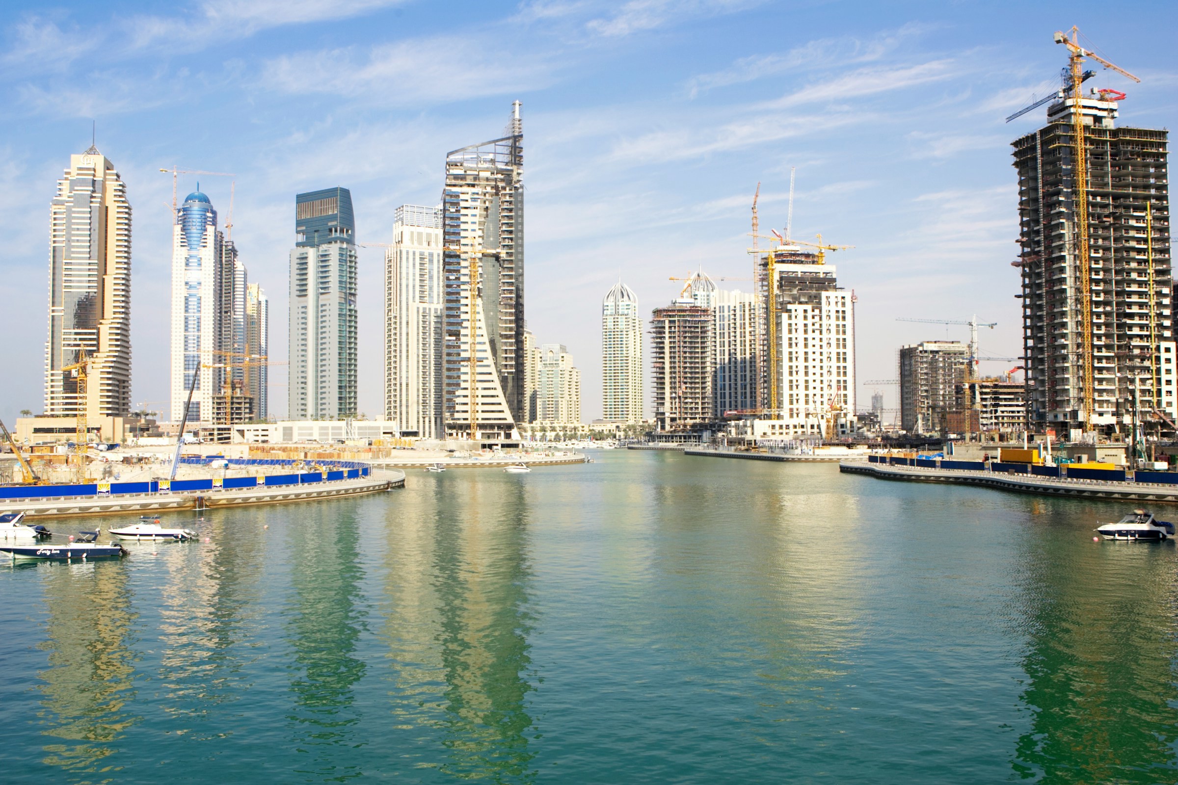 Panorama vy över vatten som möter Kuwait stad och skyskrapor med blå himmel i bakgrunden