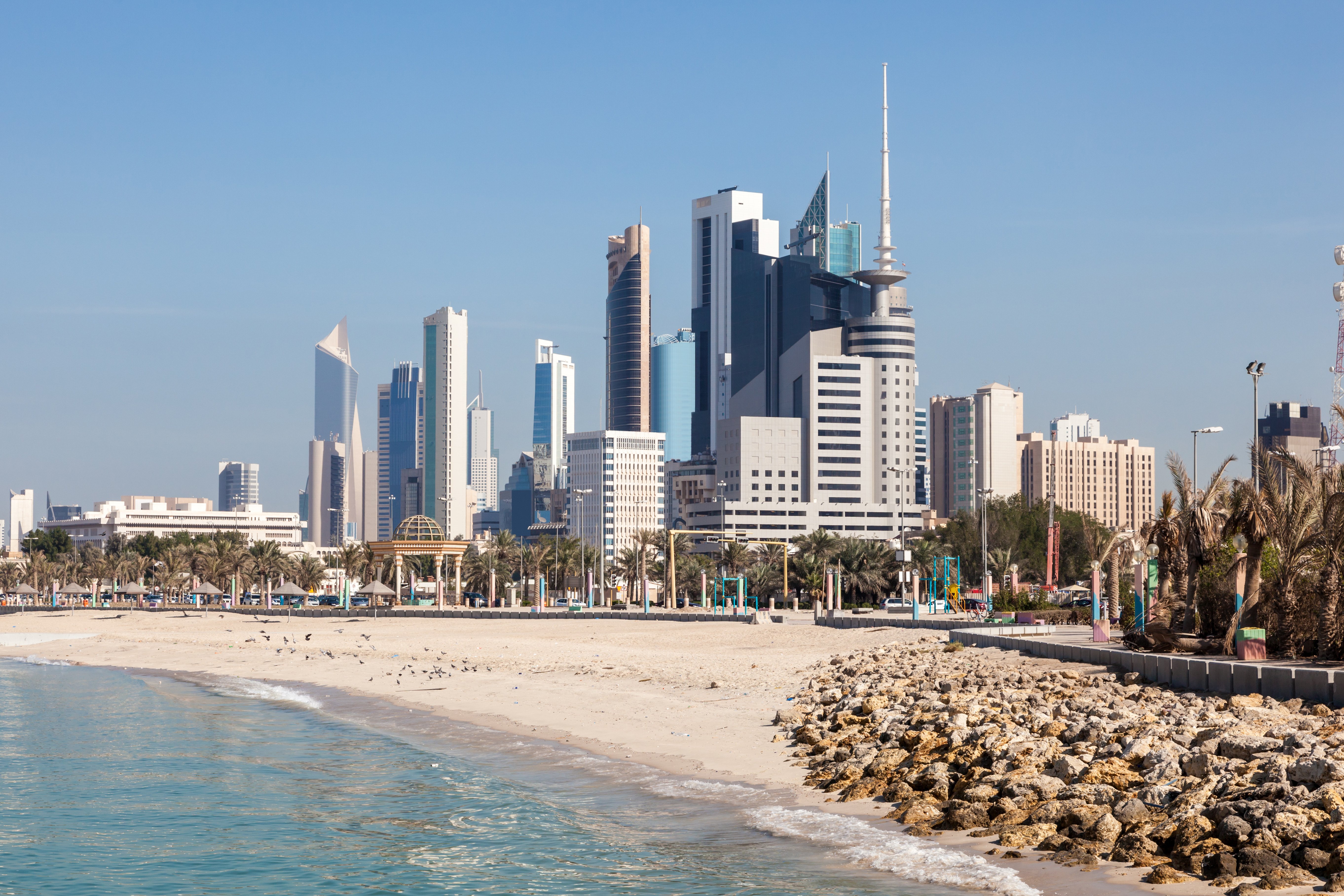 Resa till Kuwait - Stadssilhuett vid strand med moderna skyskrapor och klarblå himmel i Kuwait