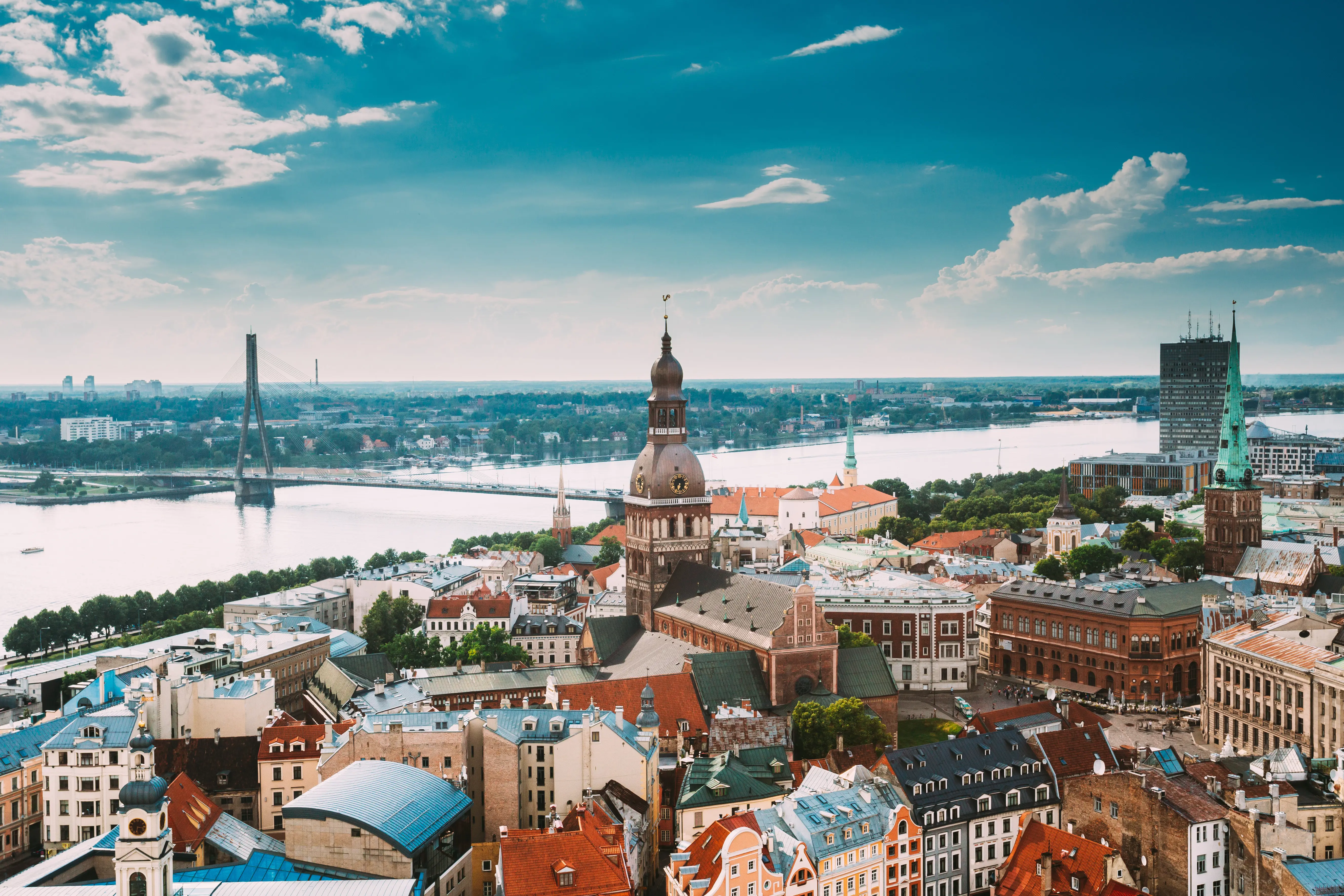 Resa till Lettland - Panoramavy över Riga med den ikoniska Riga Domkyrkan och Daugavafloden, lettiska stadssilhuetter och Vansu-bron i bakgrunden på en klar dag."