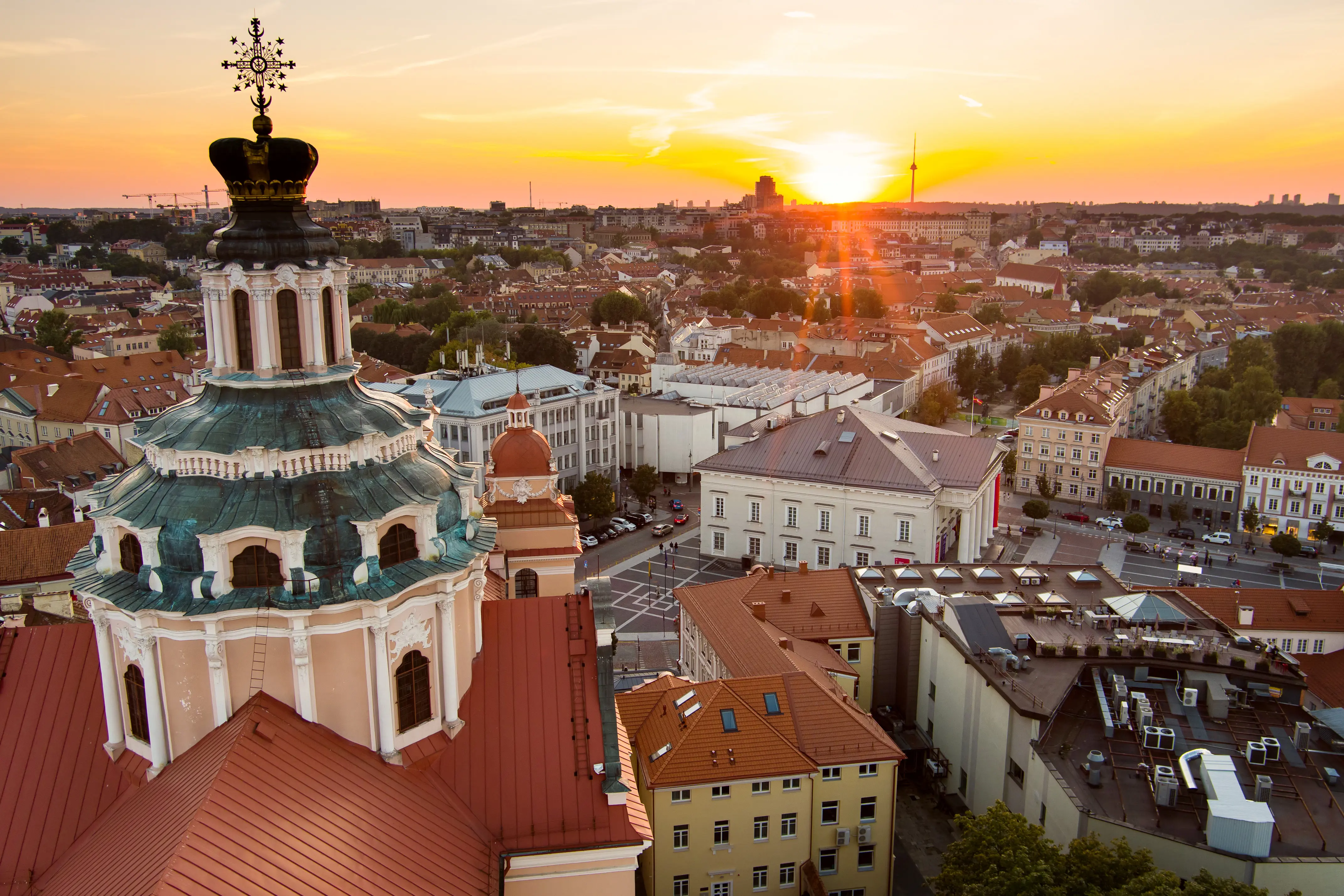 Resa till Vilnius - Solnedgång över en europeisk stad med historiska byggnader och kupoltak.