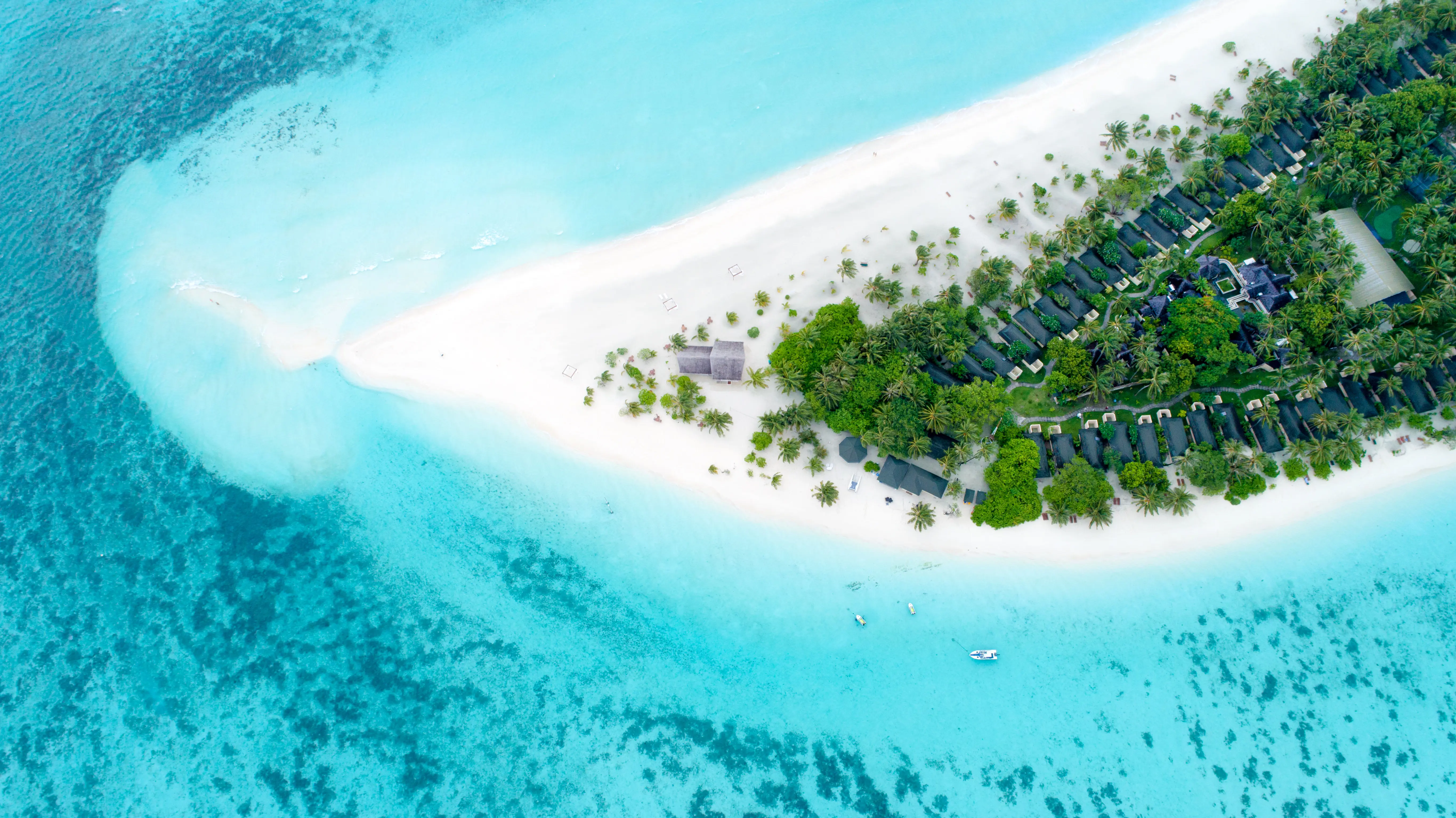 Resa till Maldiverna - Flygbild av lyxigt semesterort på tropisk strand med kristallklart vatten.