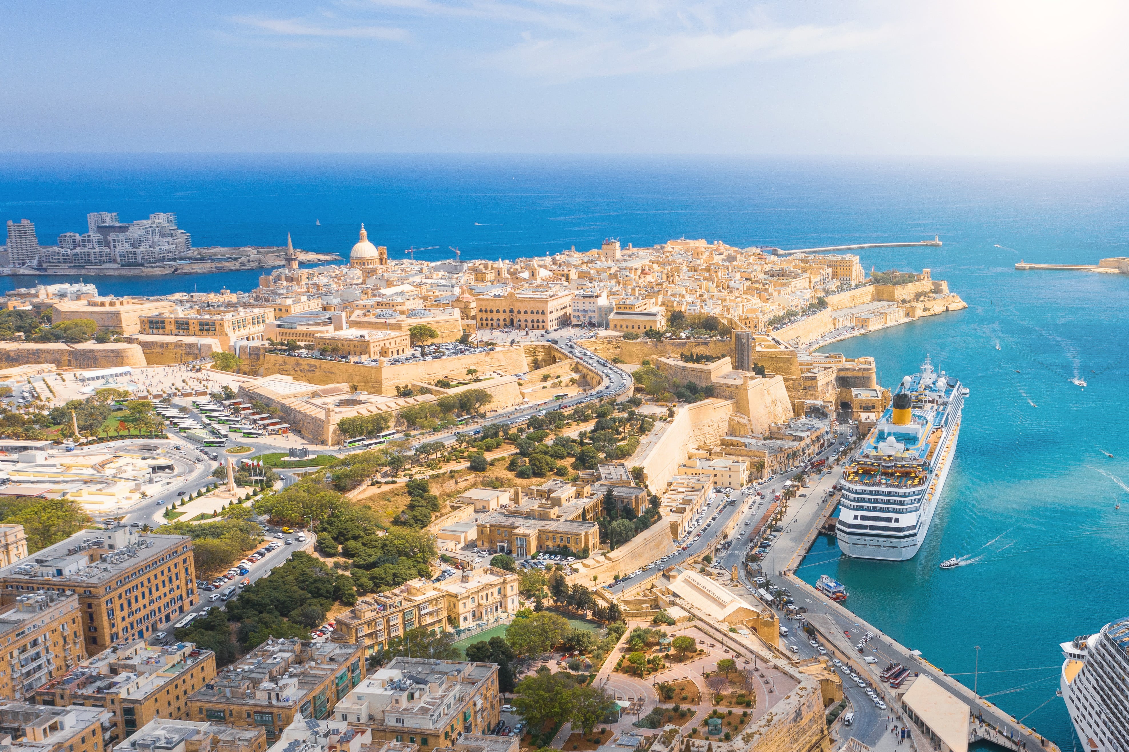 Resa till Malta - Fågelvy över kust och hamn till en vacker stad på Malta med blått hav runt sig