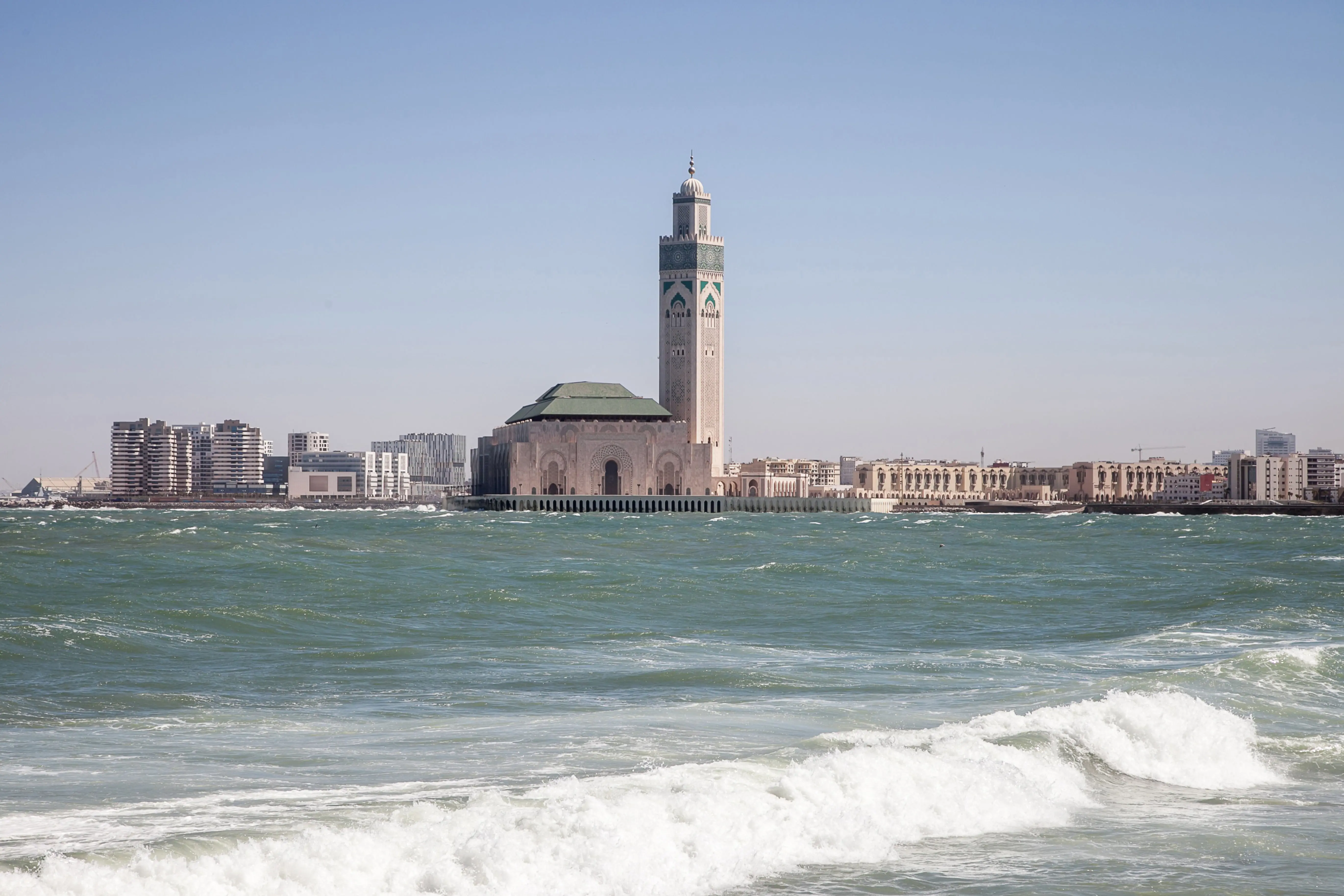 Resa till Casablanca - Strand möts av kraftiga vågor med en moské och ett vackert torn i bakgrunden som stiger upp