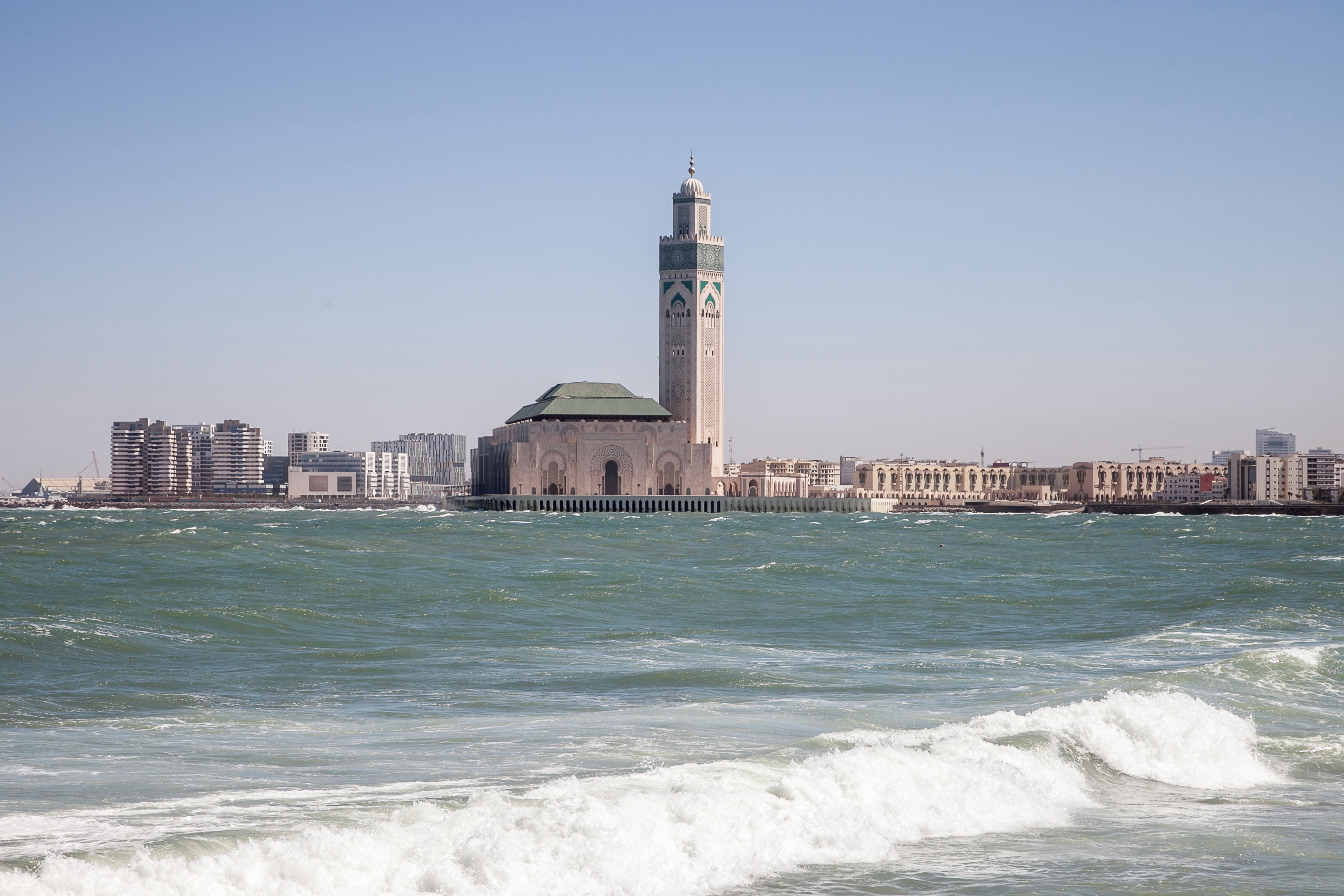 Resa till Casablanca - Strand möts av kraftiga vågor med en moské och ett vackert torn i bakgrunden som stiger upp